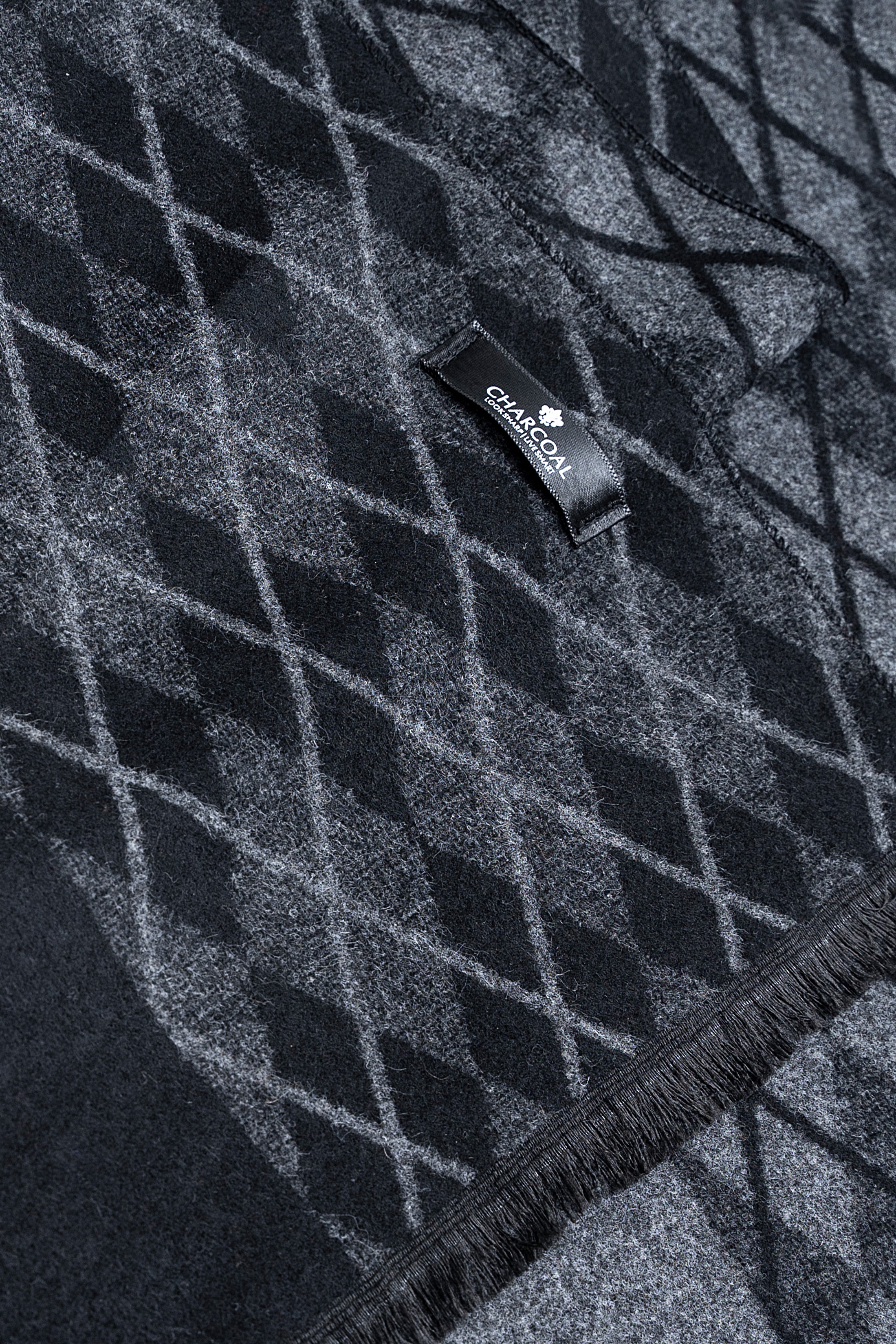 Dark scarf fabric with gray diamond weave pattern and small brand label