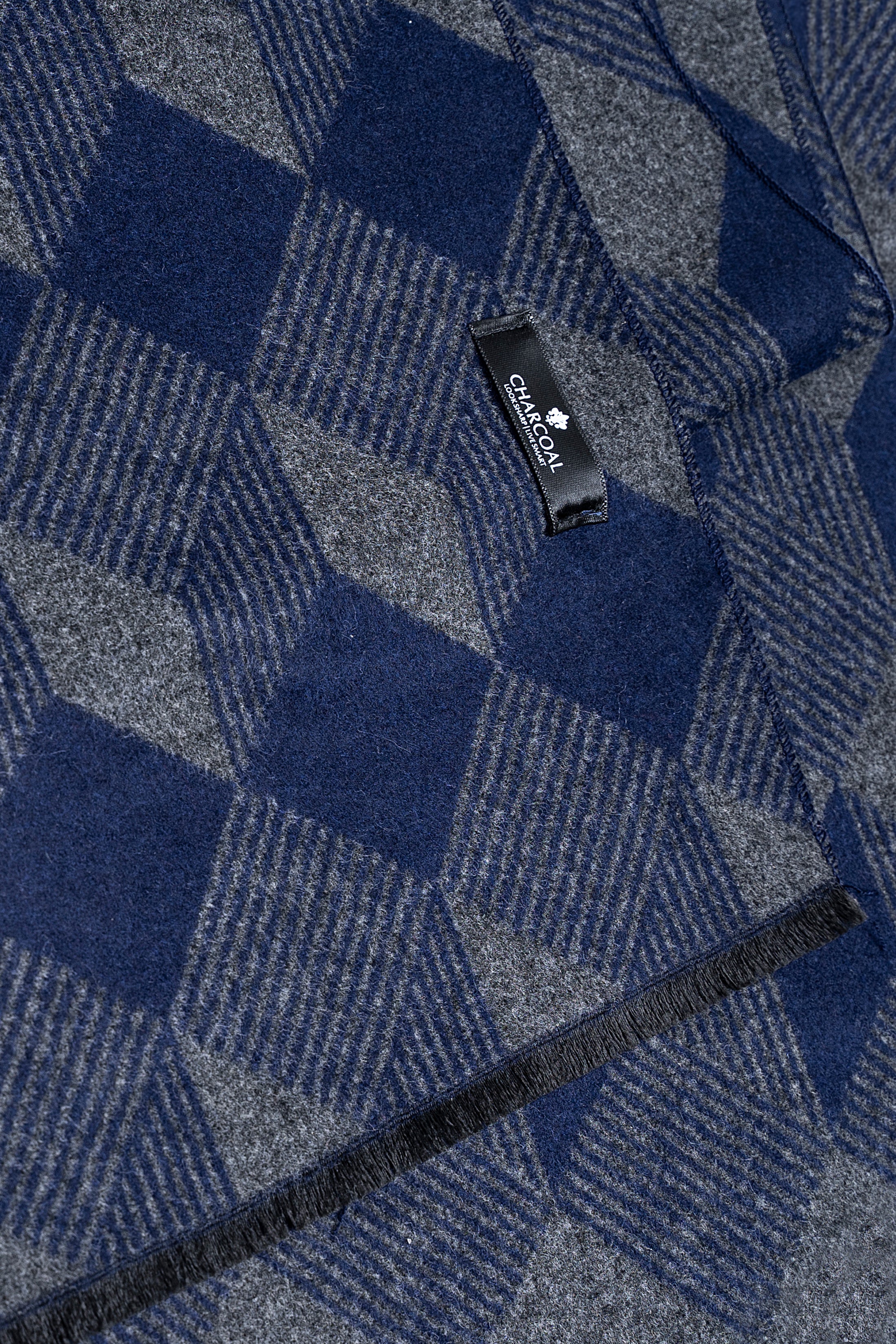 Close-up of blue and gray diamond-pattern scarf fabric with small woven label