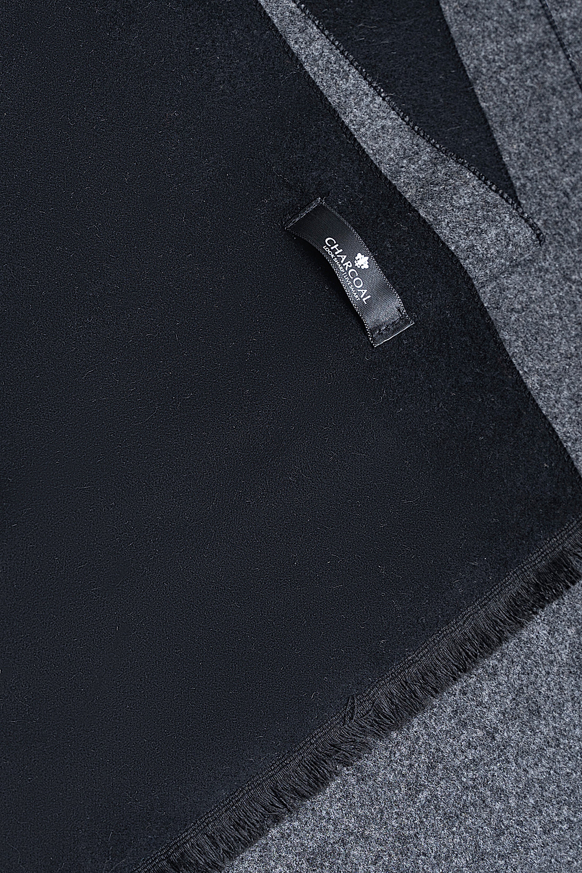 Dark scarf close-up with stitched label and fringed trim