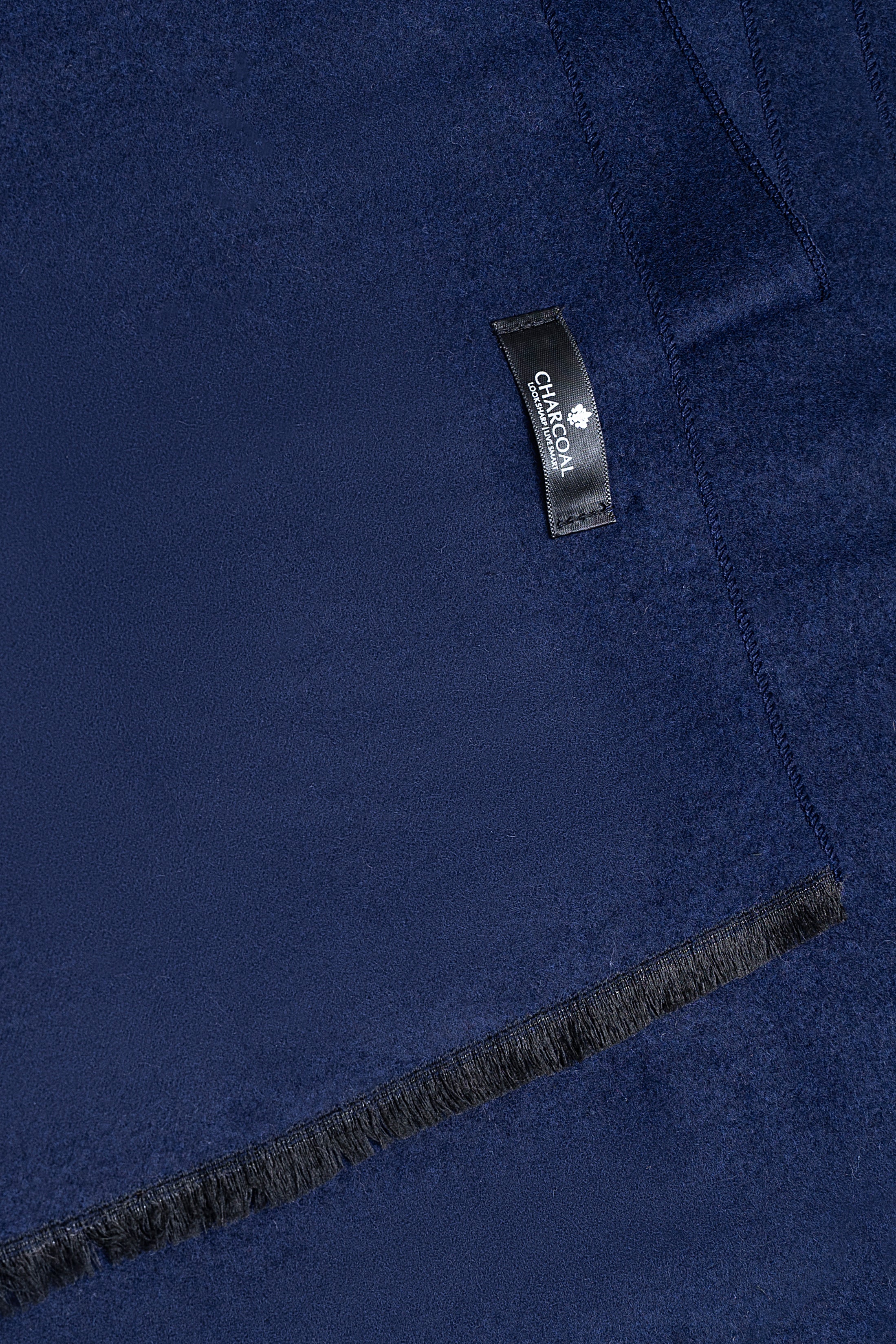Navy blue scarf fabric close-up with brand label and visible stitched seam