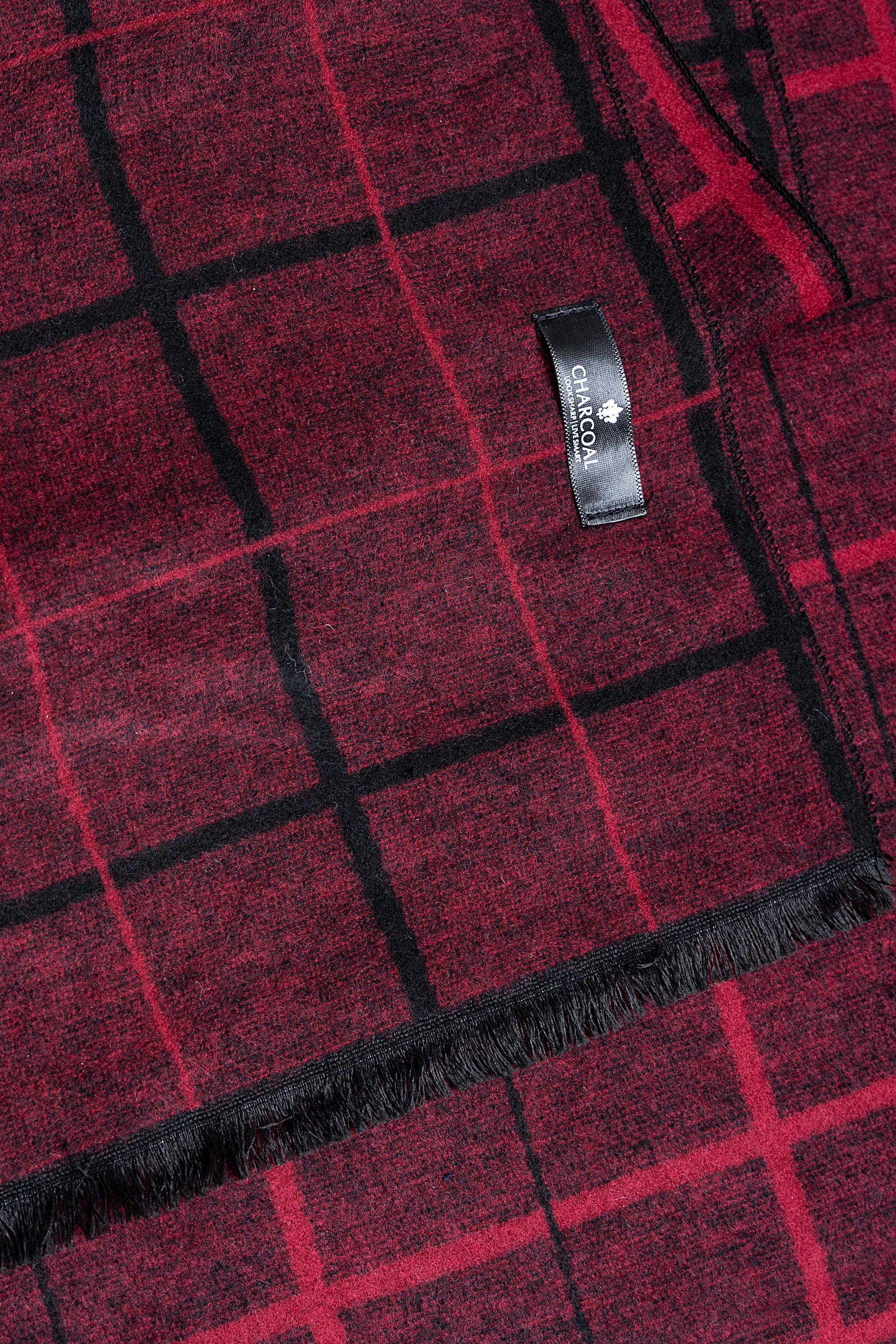 Burgundy scarf close-up with black check grid, stitched label, and fringed edge.