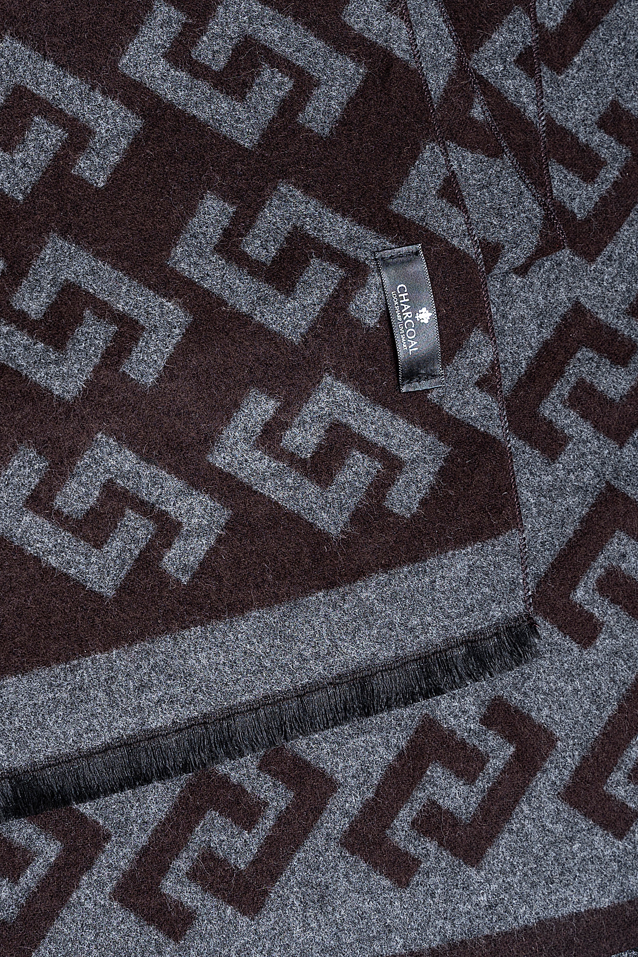 Charcoal and gray Greek-key scarf close-up with woven label and fringe