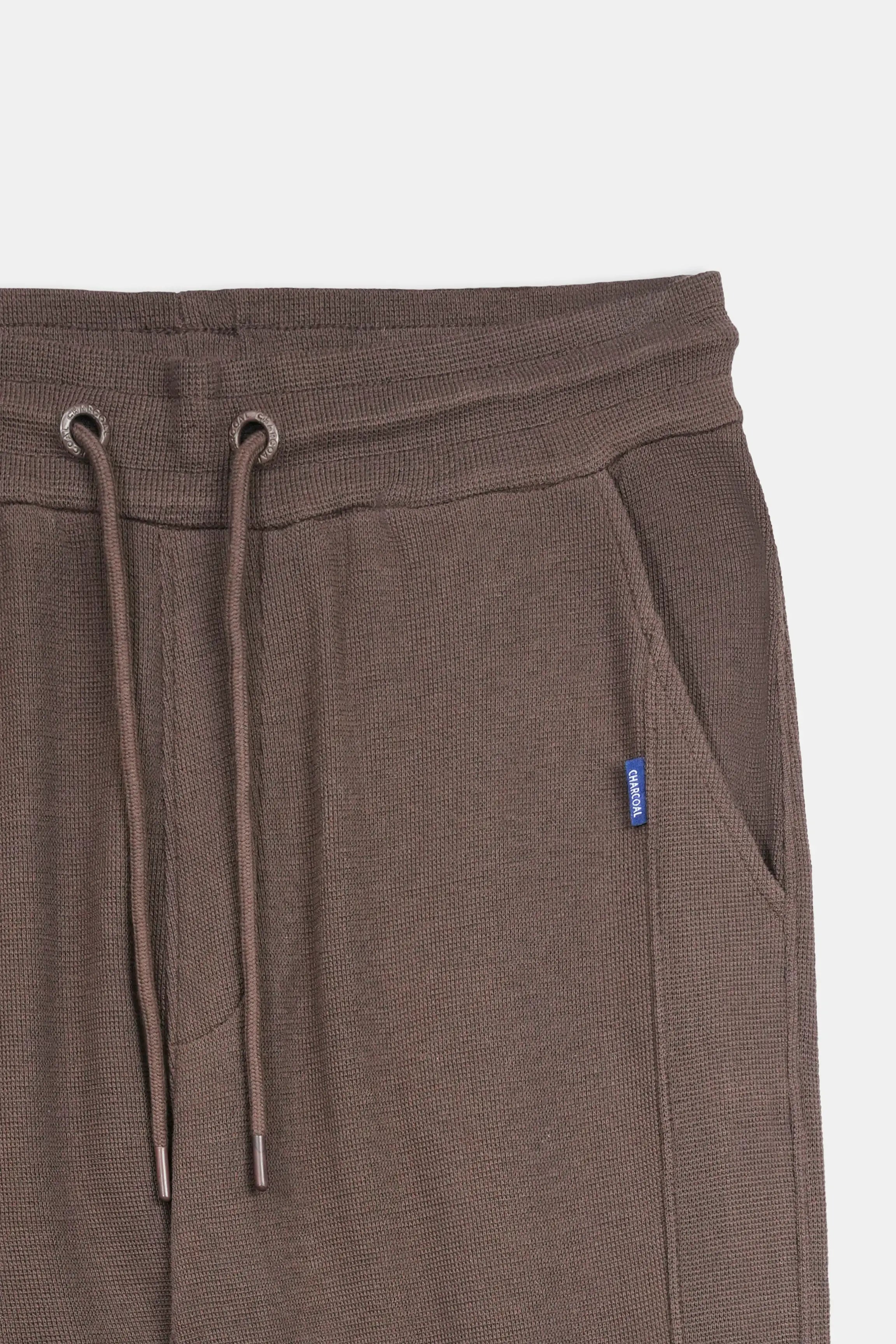 Brown knit trousers close-up with drawstring waist and side pocket
