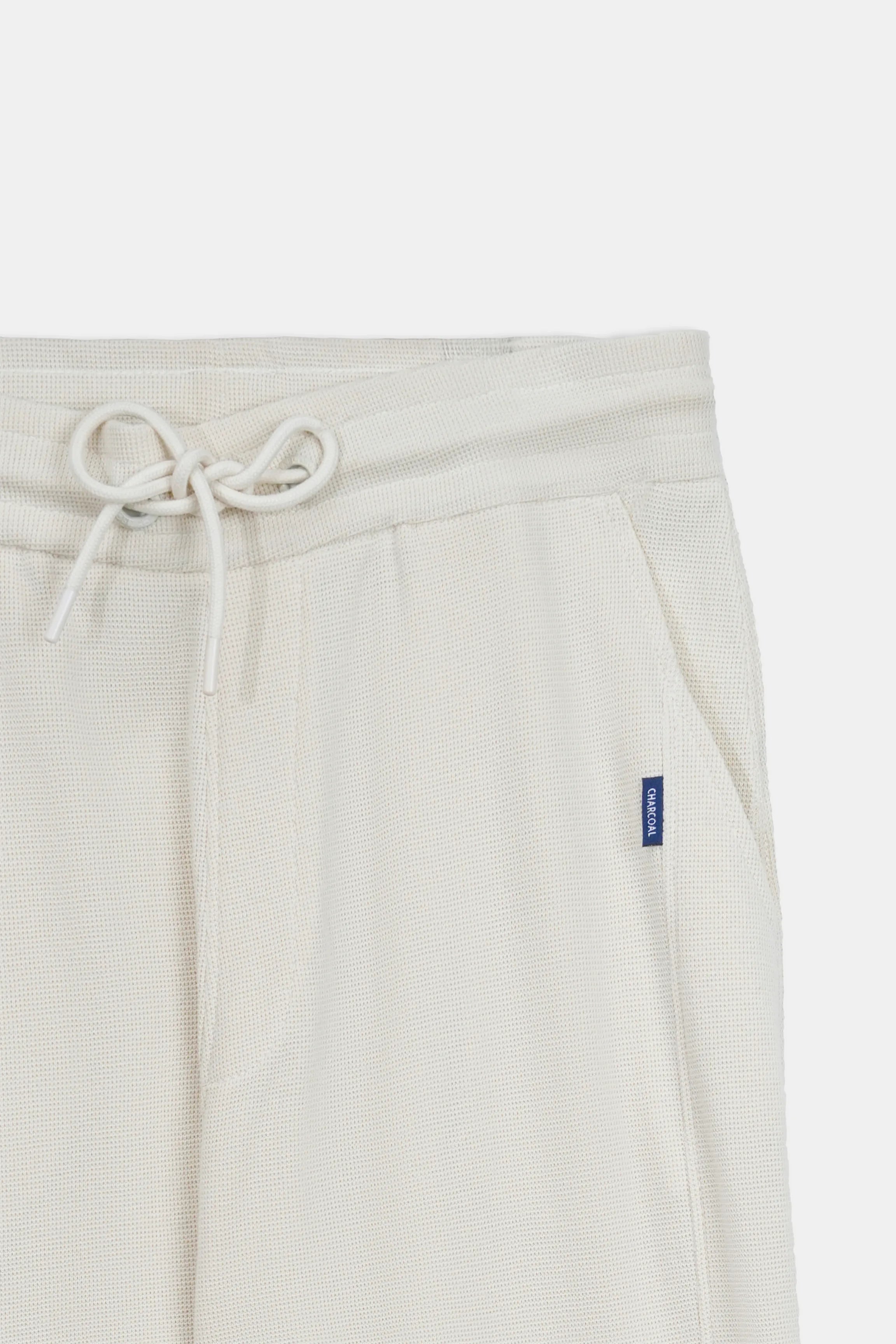 Off-white knit waistband with drawstring and blue logo tag