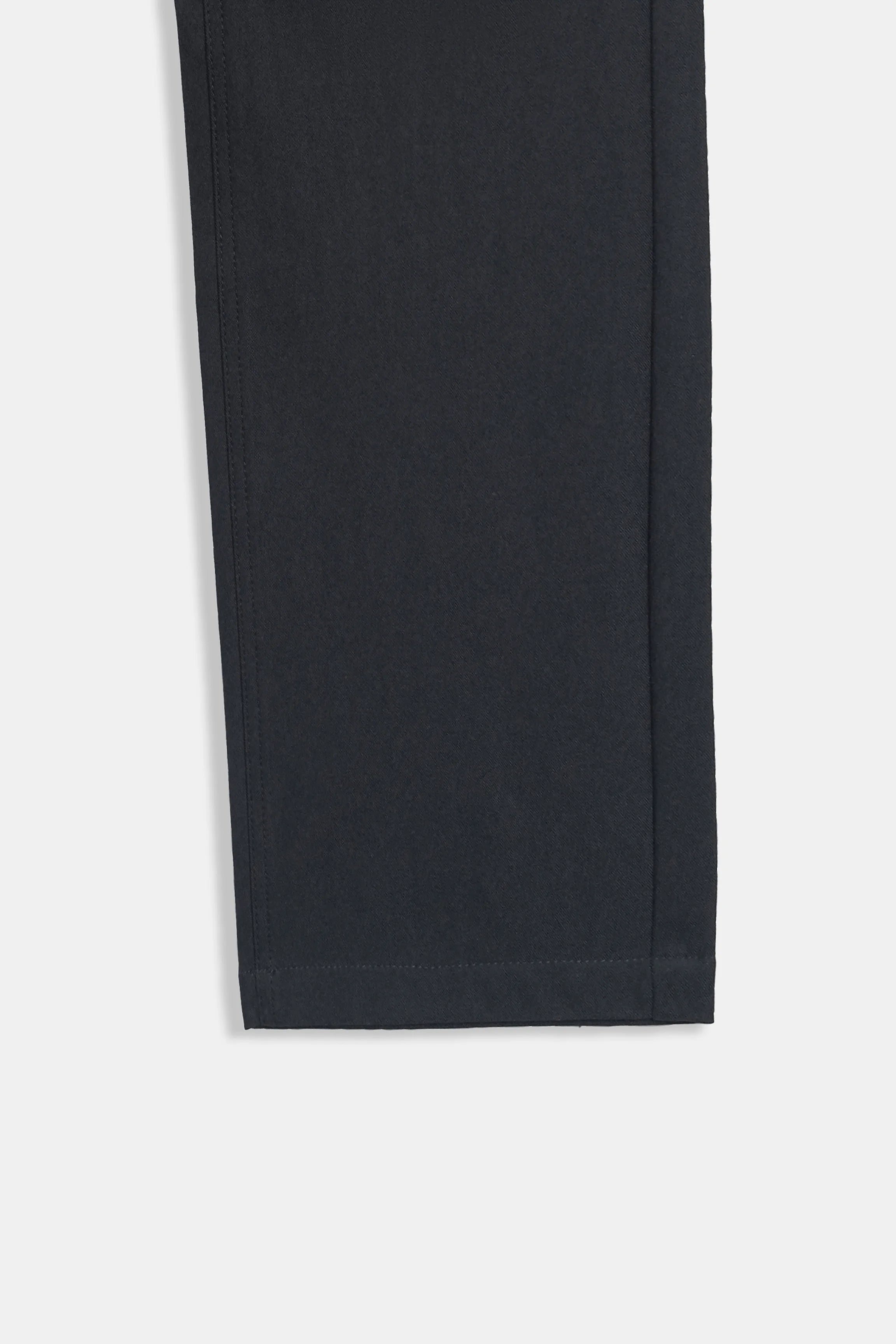 Black straight-fit travel pants hem with neat stitching, ankle-length