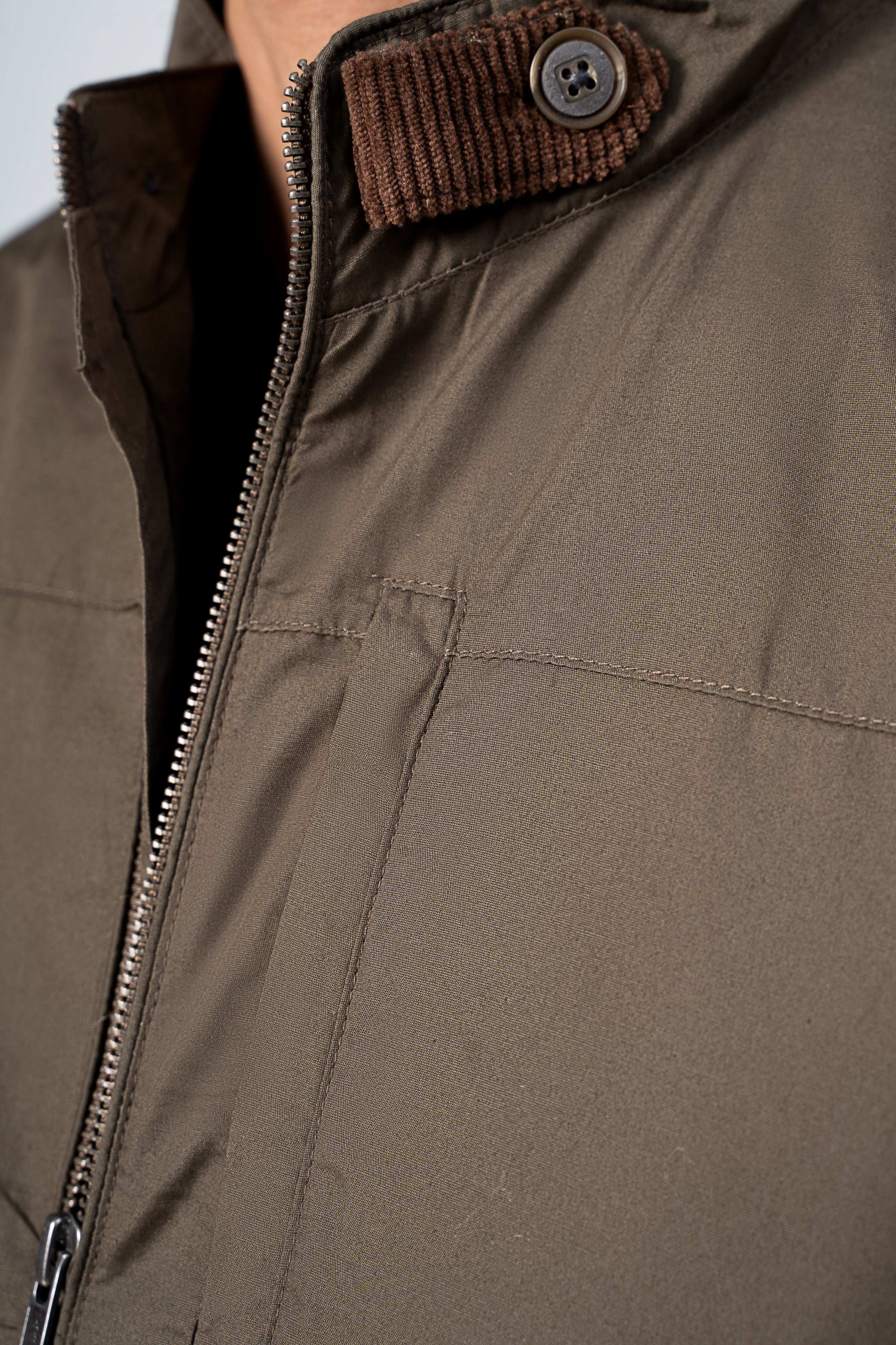 Padded cotton jacket detail: olive-brown zip and rib-knit collar with button