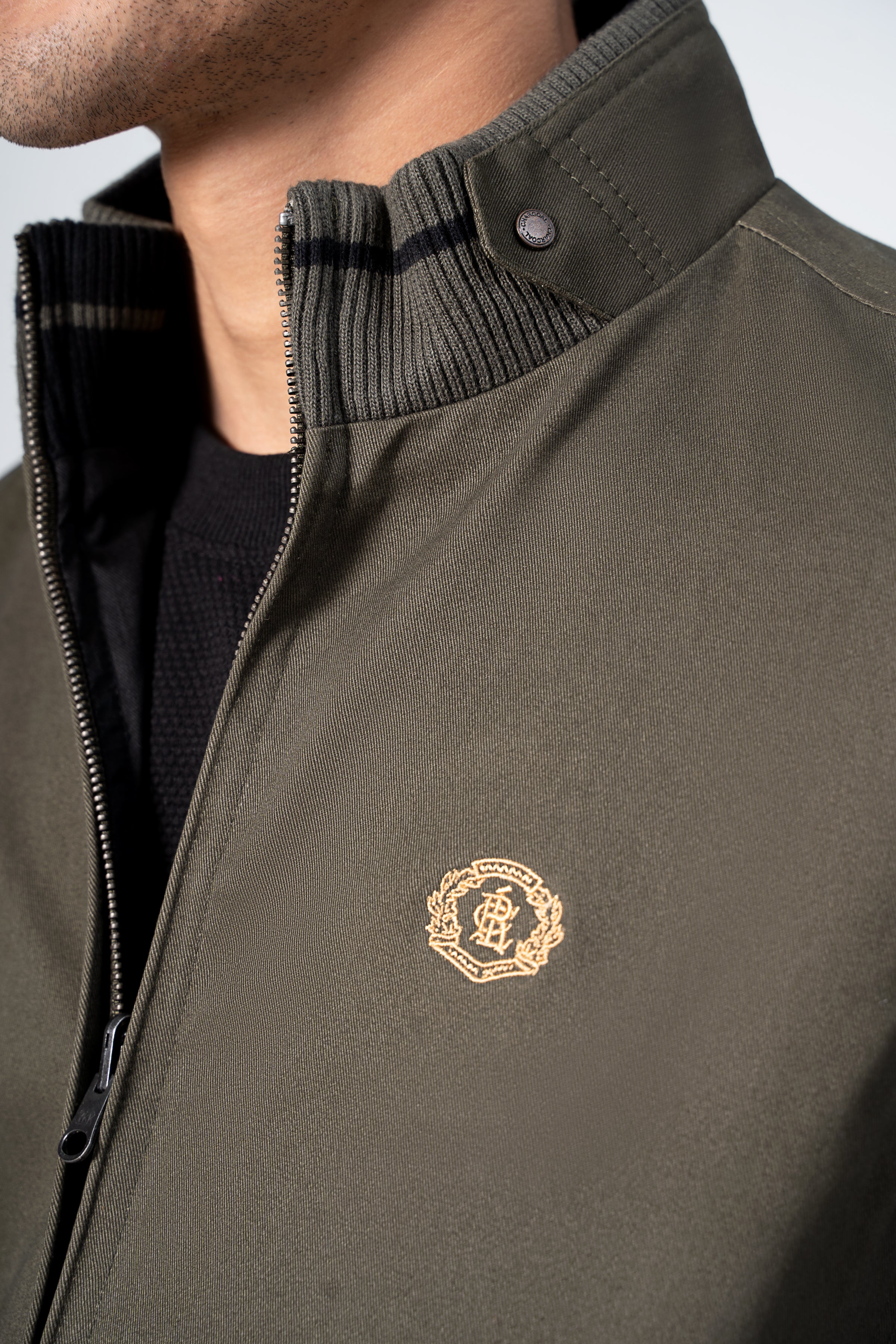 Reversible jacket collar detail in olive with snap button and embroidered crest