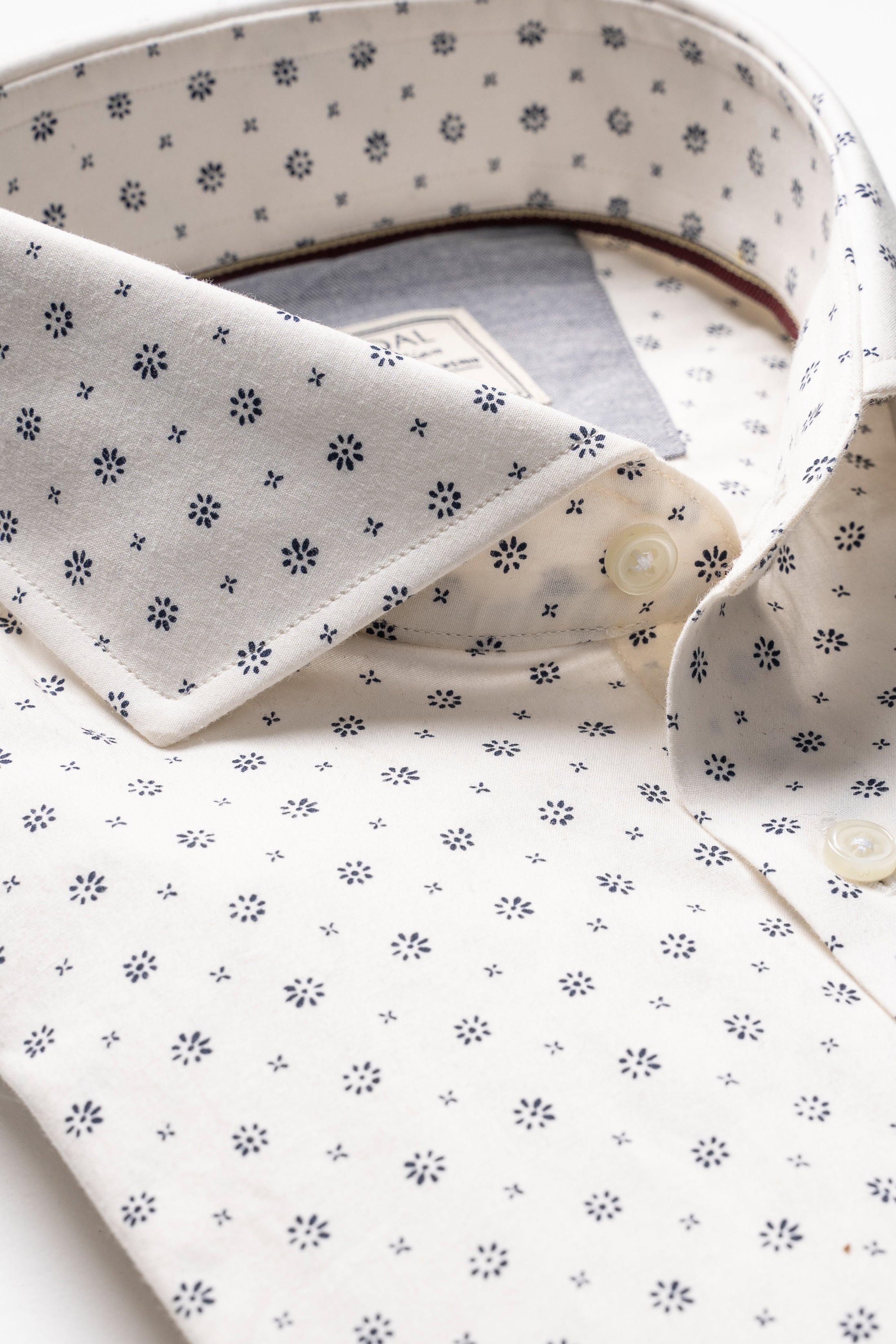 White dress shirt with small navy floral dot pattern, buttoned collar detail