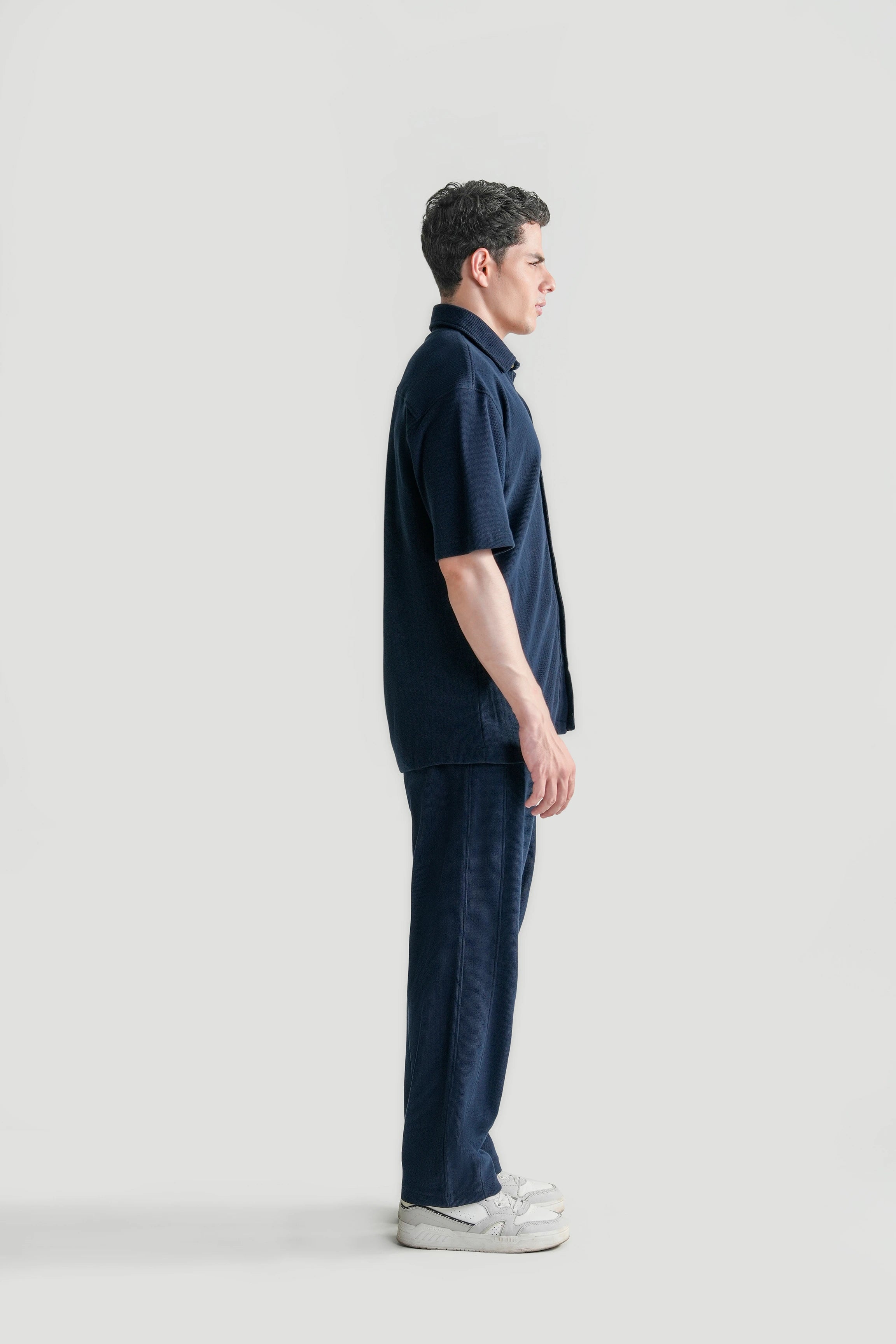 Navy short-sleeve knit button-up casual shirt with front pocket, side view.