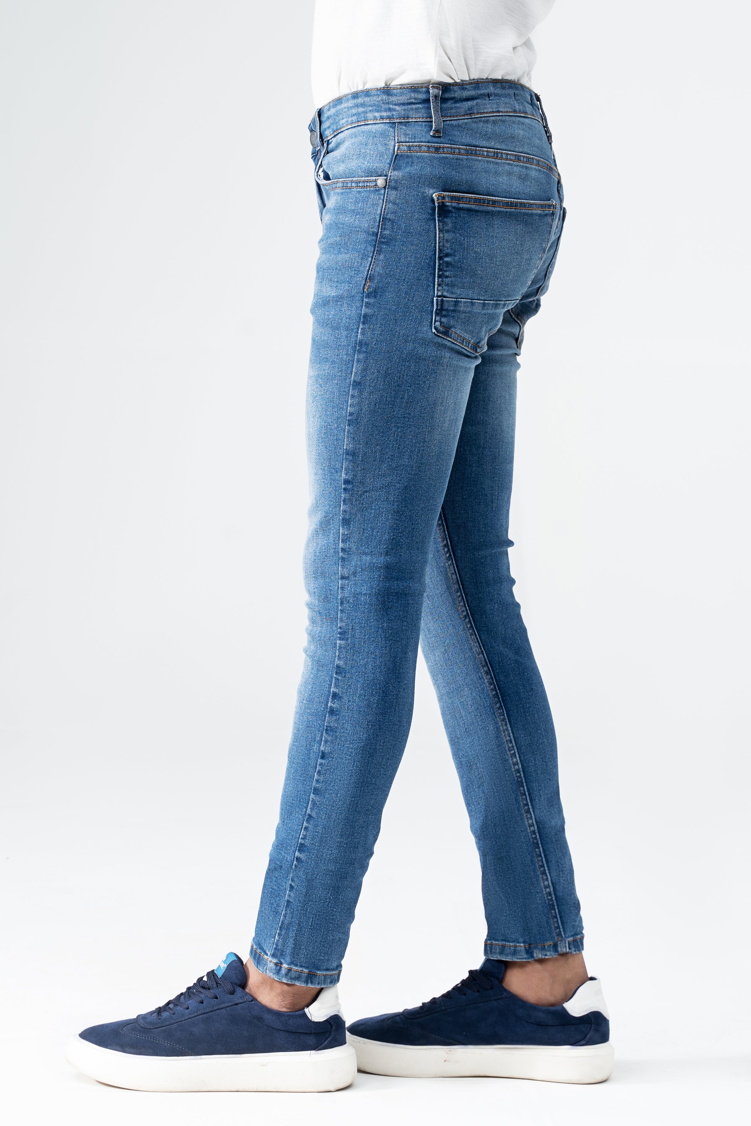 Men's slim-fit mid-blue denim jeans, back view with tapered legs and rear pockets