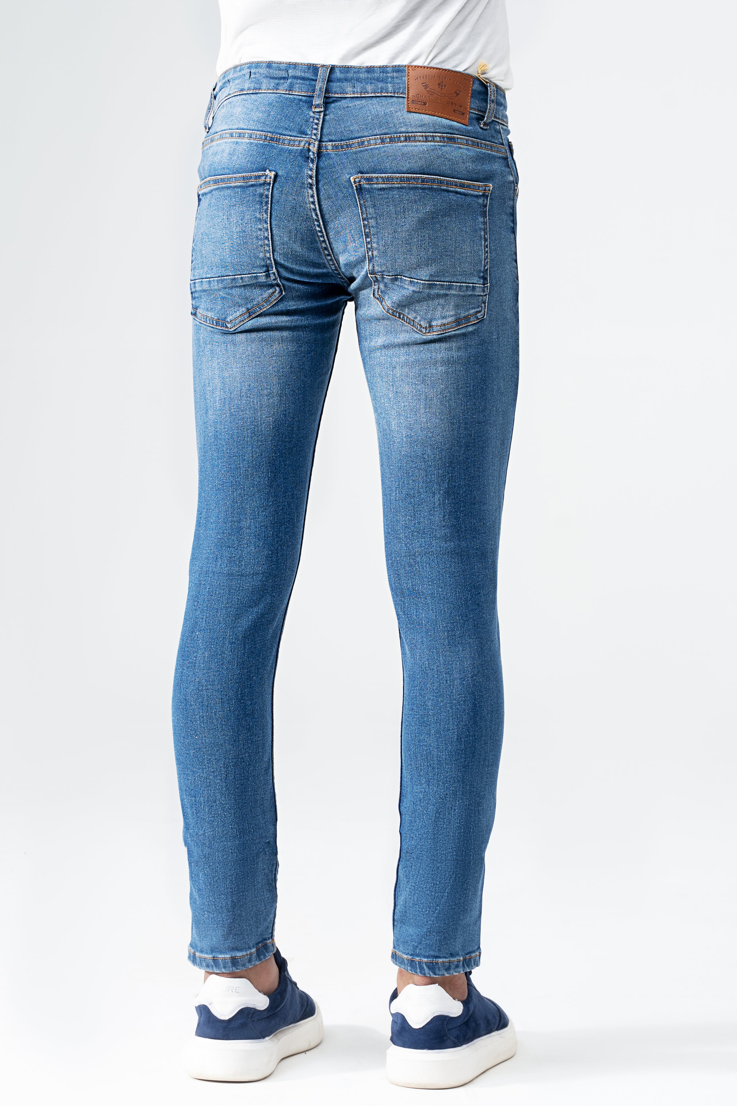Men's slim-fit mid-blue denim jeans, back view with brown waist patch and rear pockets