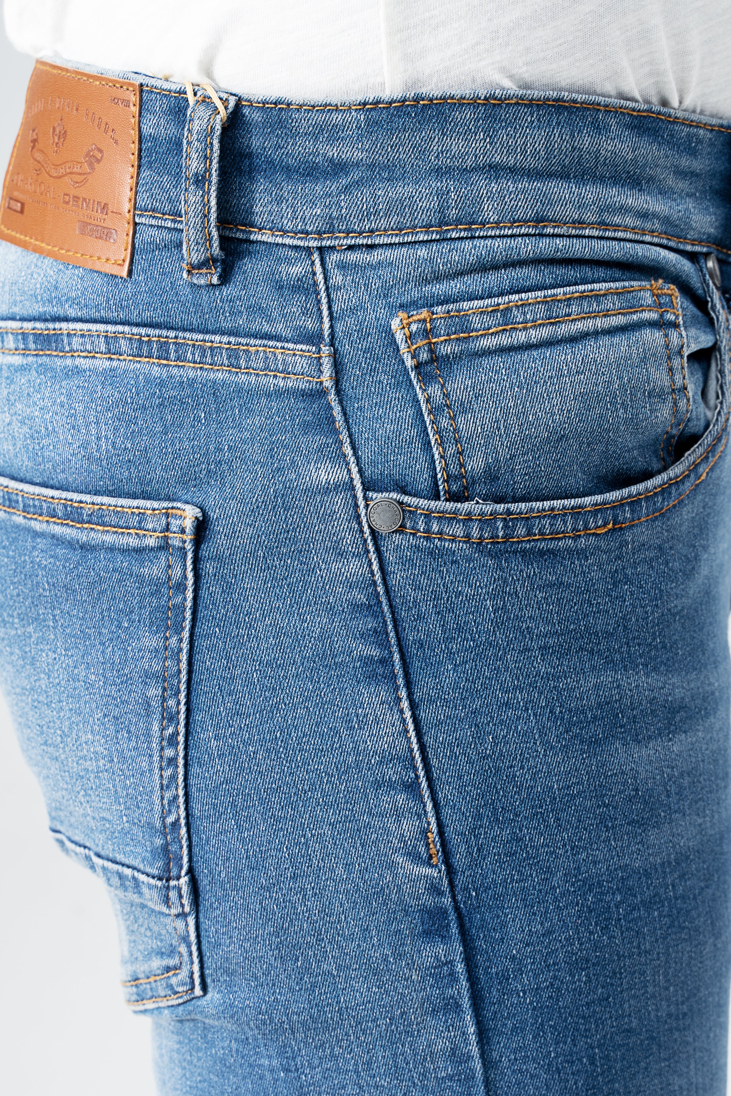 Men's mid-blue denim jeans close-up of front pocket, zipper fly, and belt loops