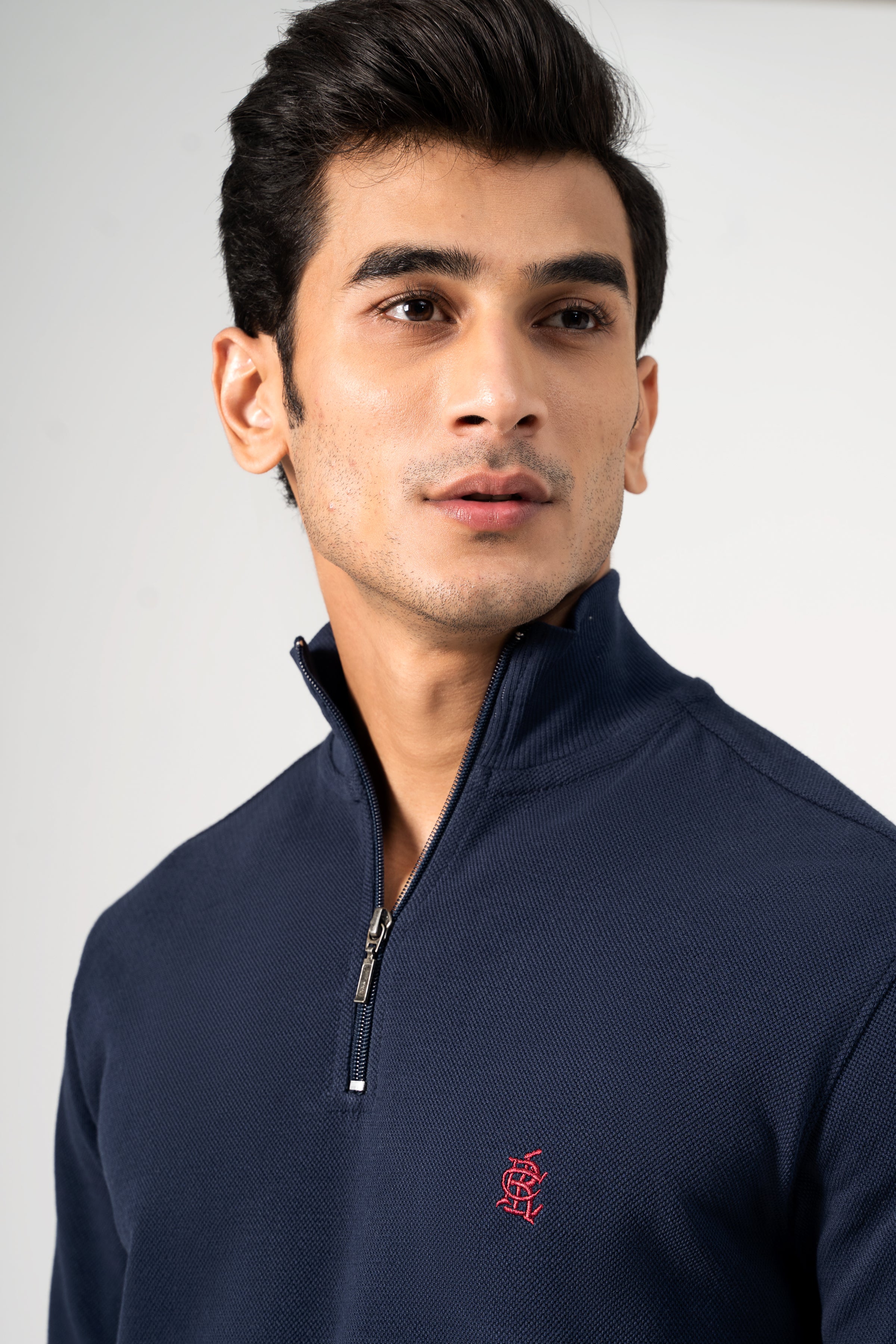 Navy mock-neck sweatshirt with quarter-zip and small red crest logo at chest