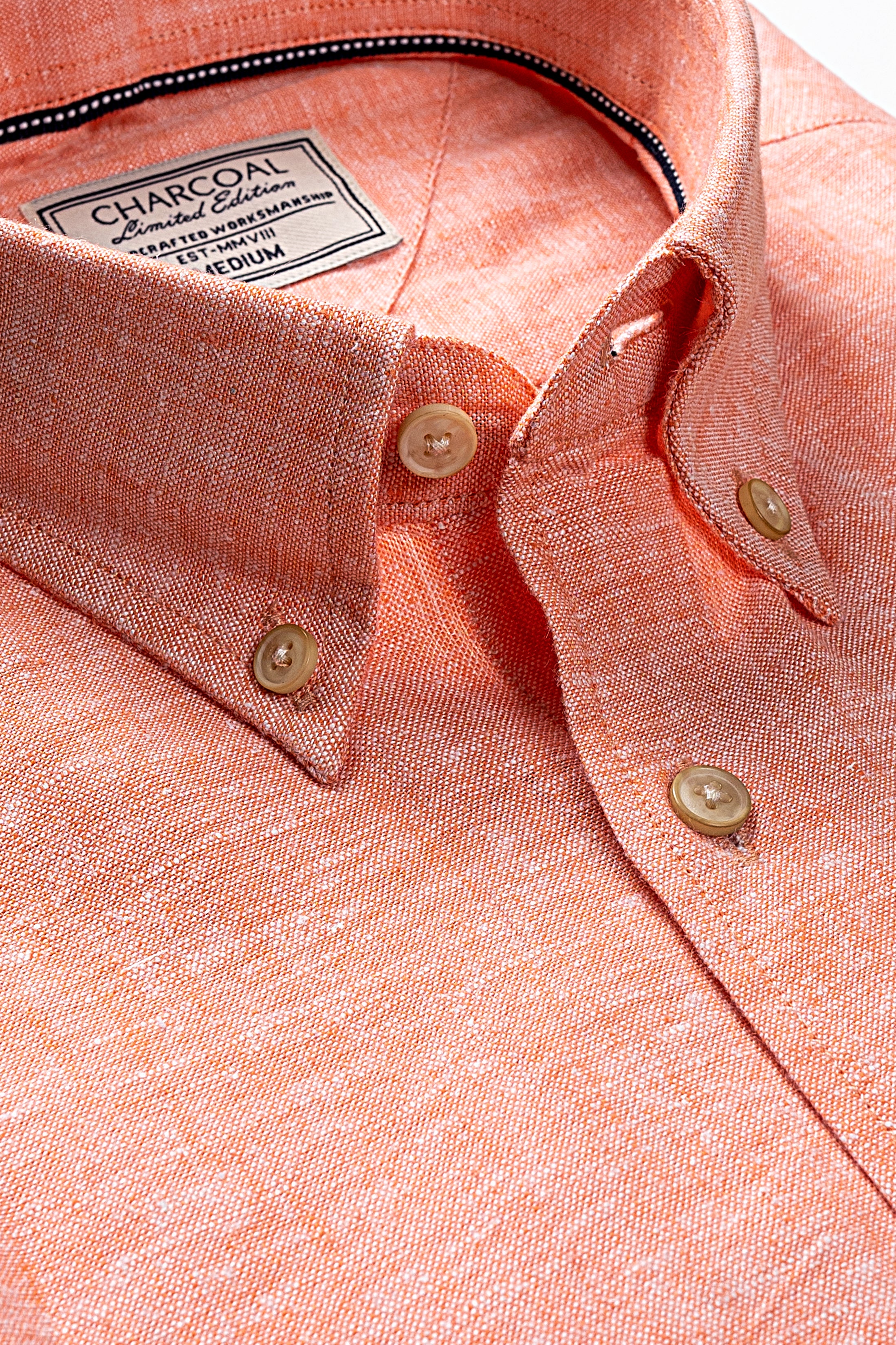 Peach linen shirt close-up: buttoned collar, gold-tone buttons, and front placket