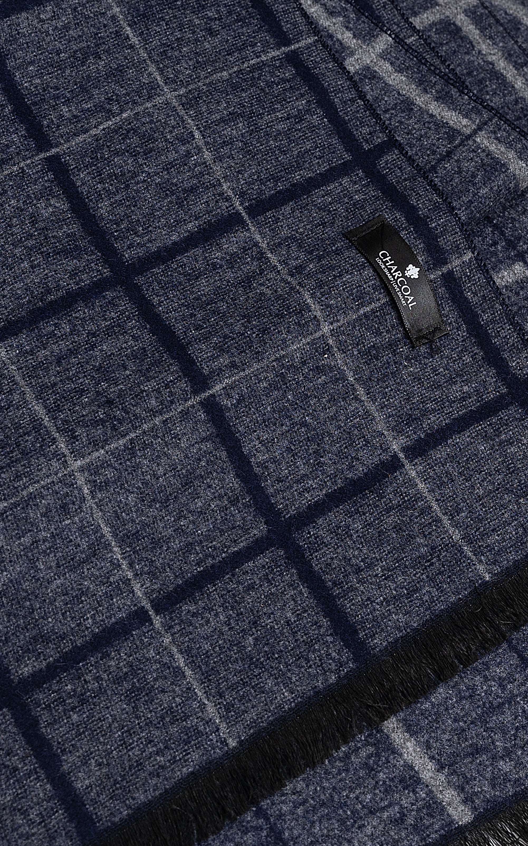 Dark grid-pattern scarf fabric with small logo tag and textured weave.