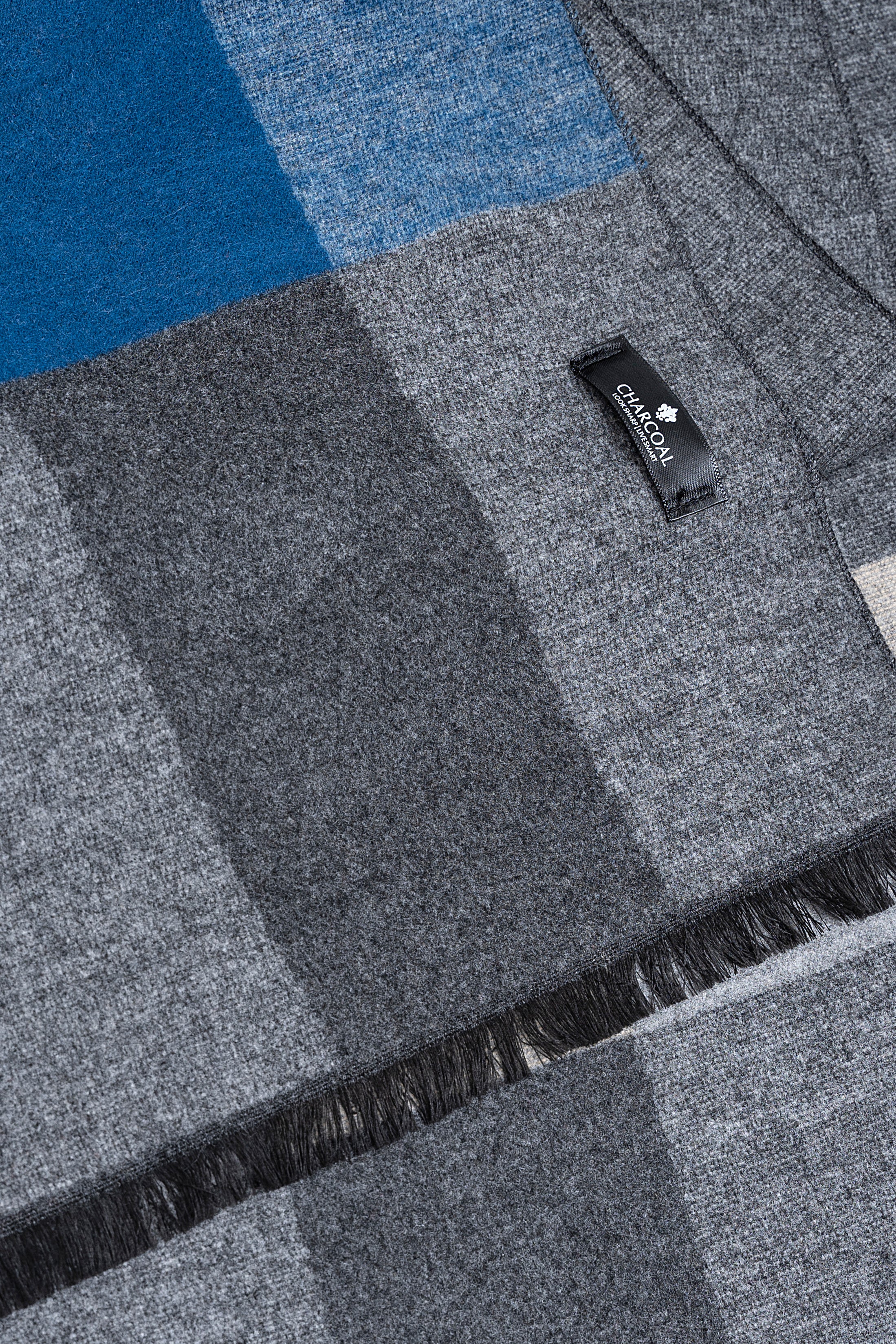 Gray plaid scarf close-up with blue-and-light panels, woven texture and fringe.