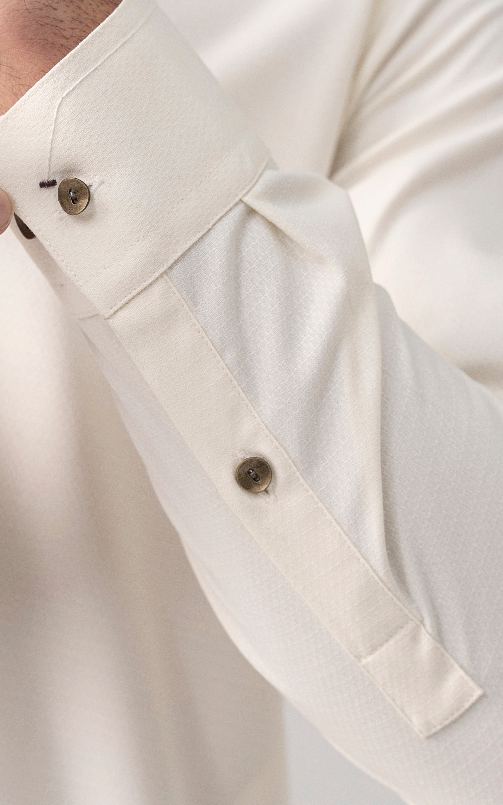 Off-white kurta placket close-up with gold-tone buttons
