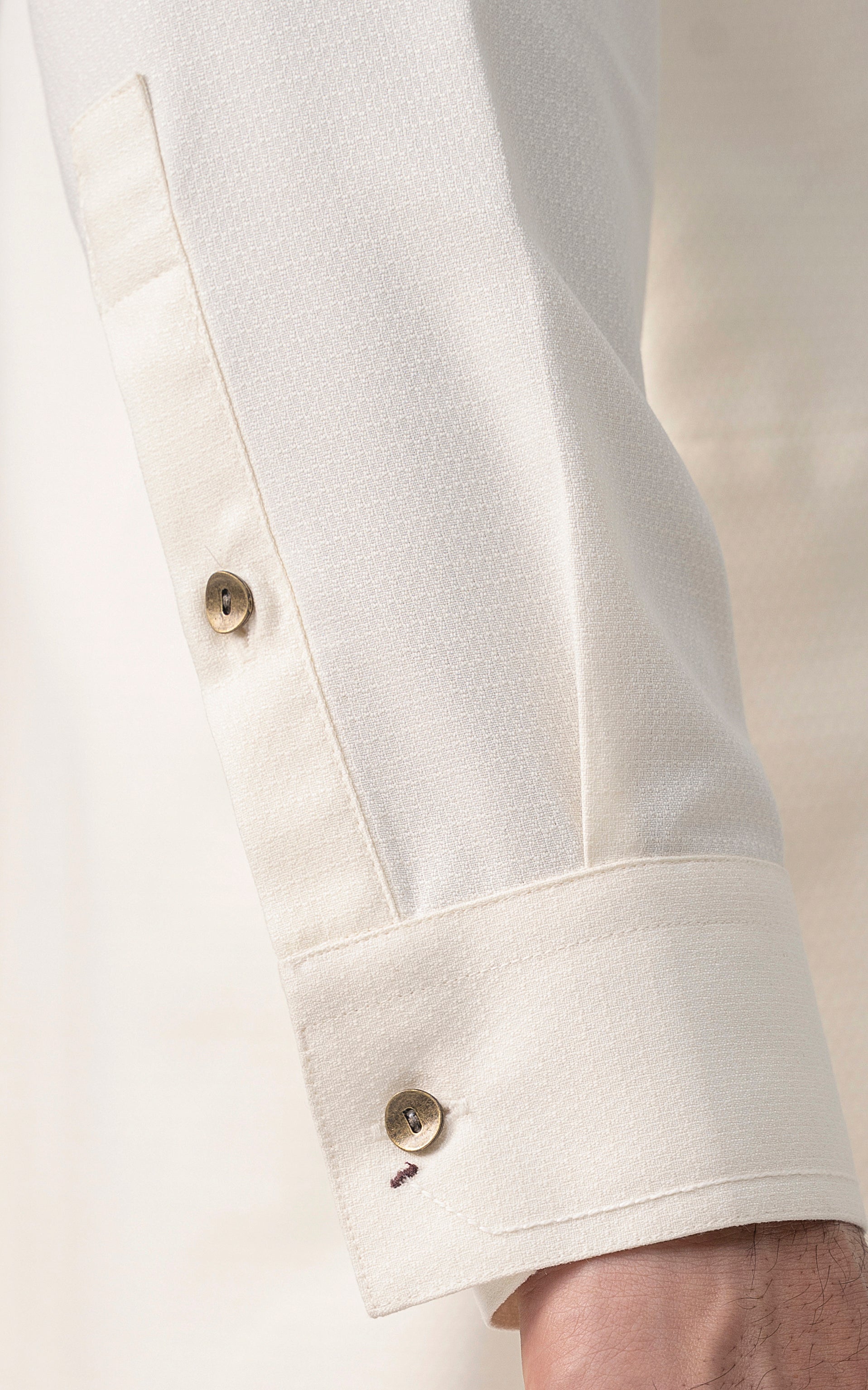 Off-white kurta sleeve cuff with gold-tone button