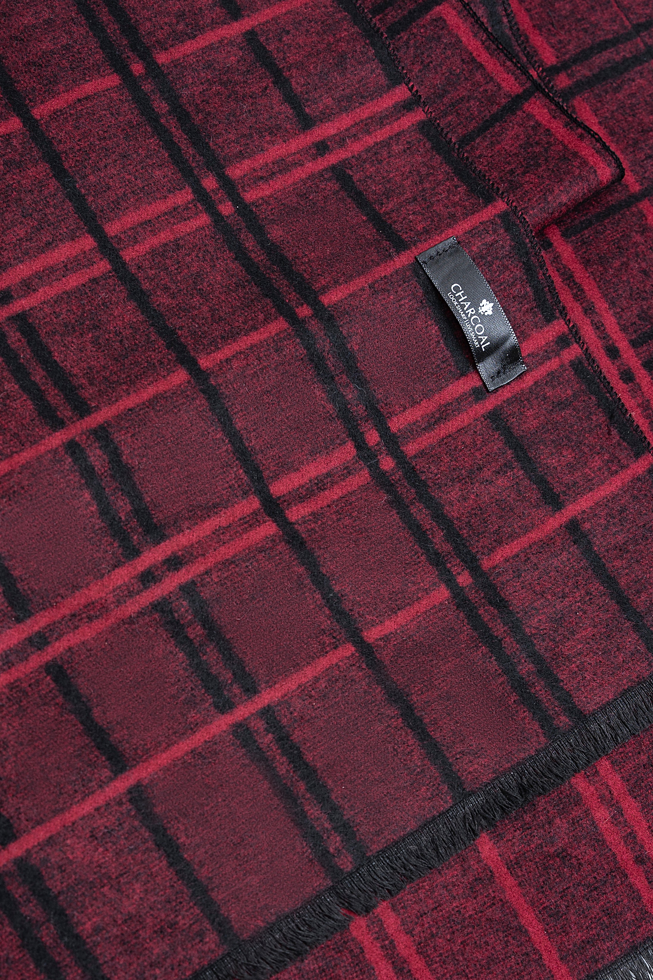 Plaid scarf fabric close-up in burgundy with dark grid lines and woven brand label