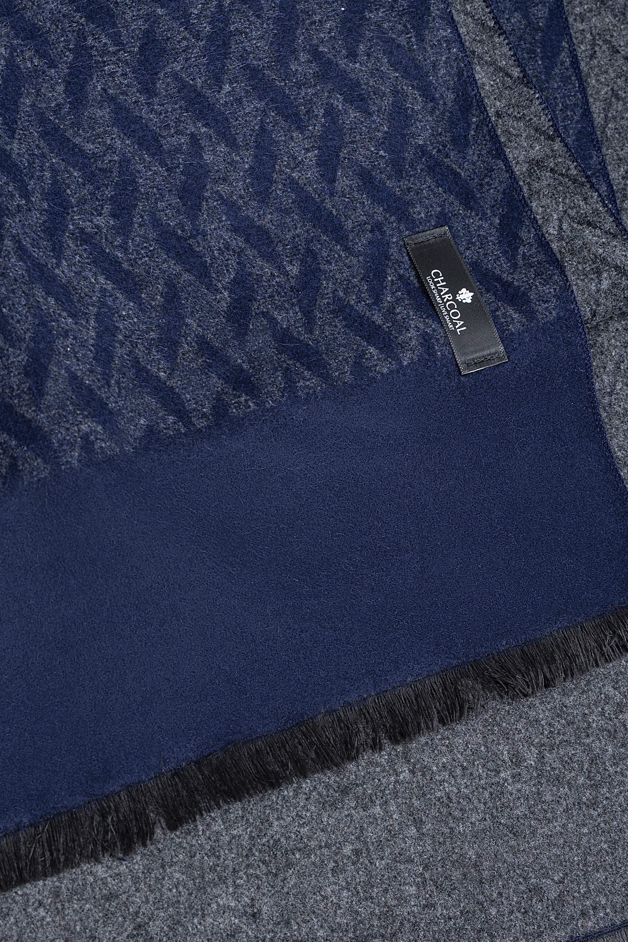 Navy scarf fabric close-up with zigzag texture, brand label, and fringed edge