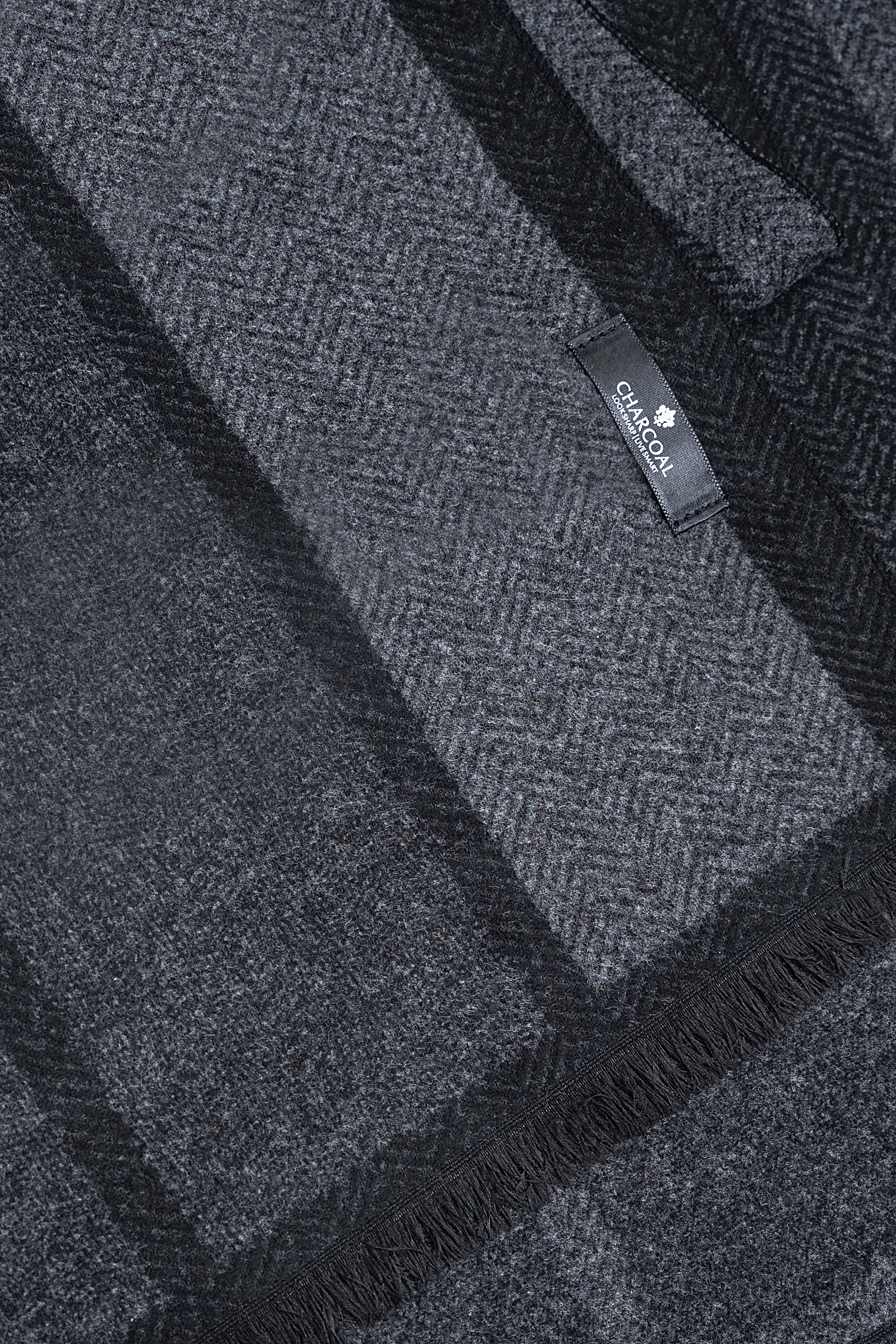 Dark navy scarf with woven stripe pattern and fringe trim, logo label near edge.