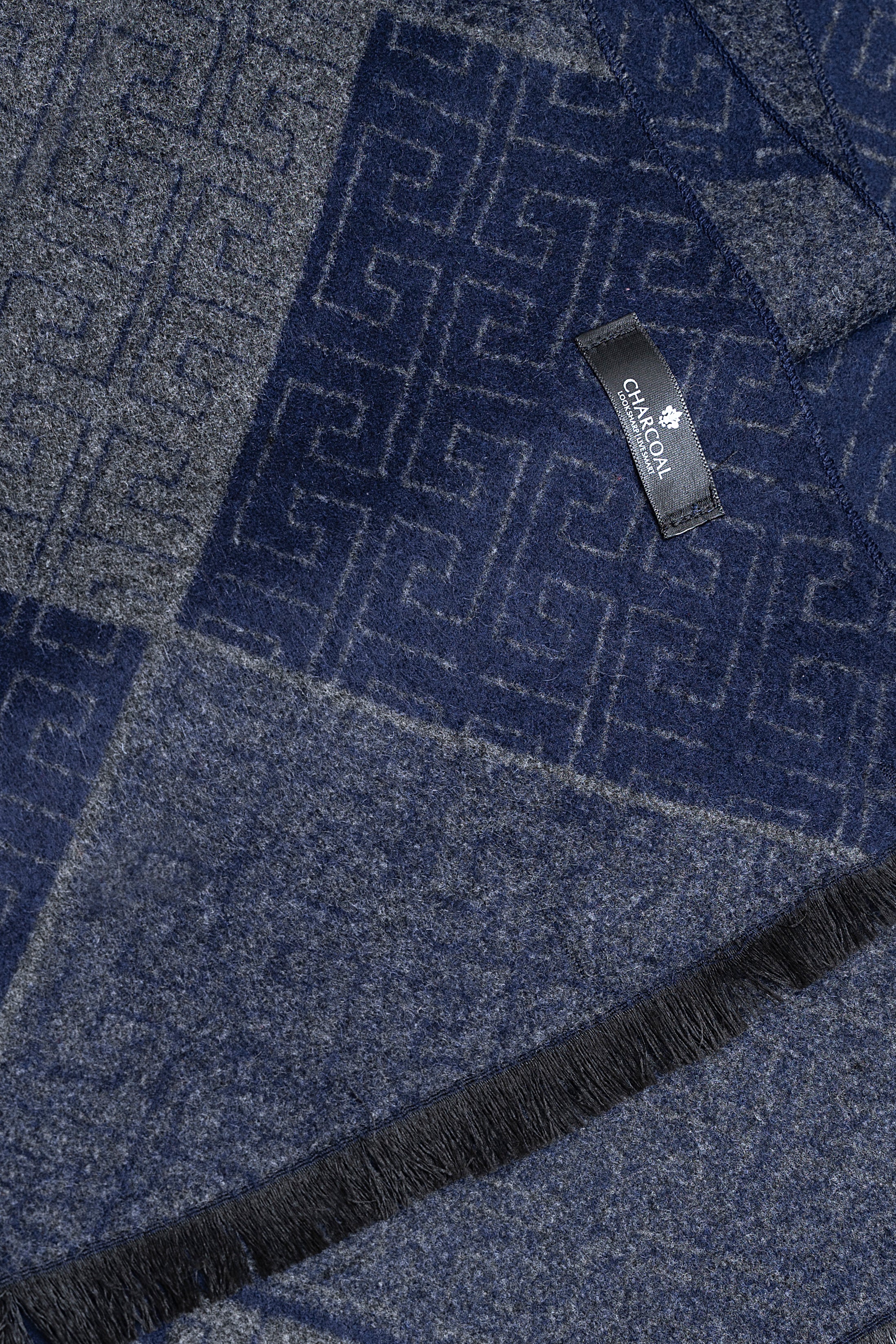 Blue and gray patterned scarf close-up with brand tag and fringed border