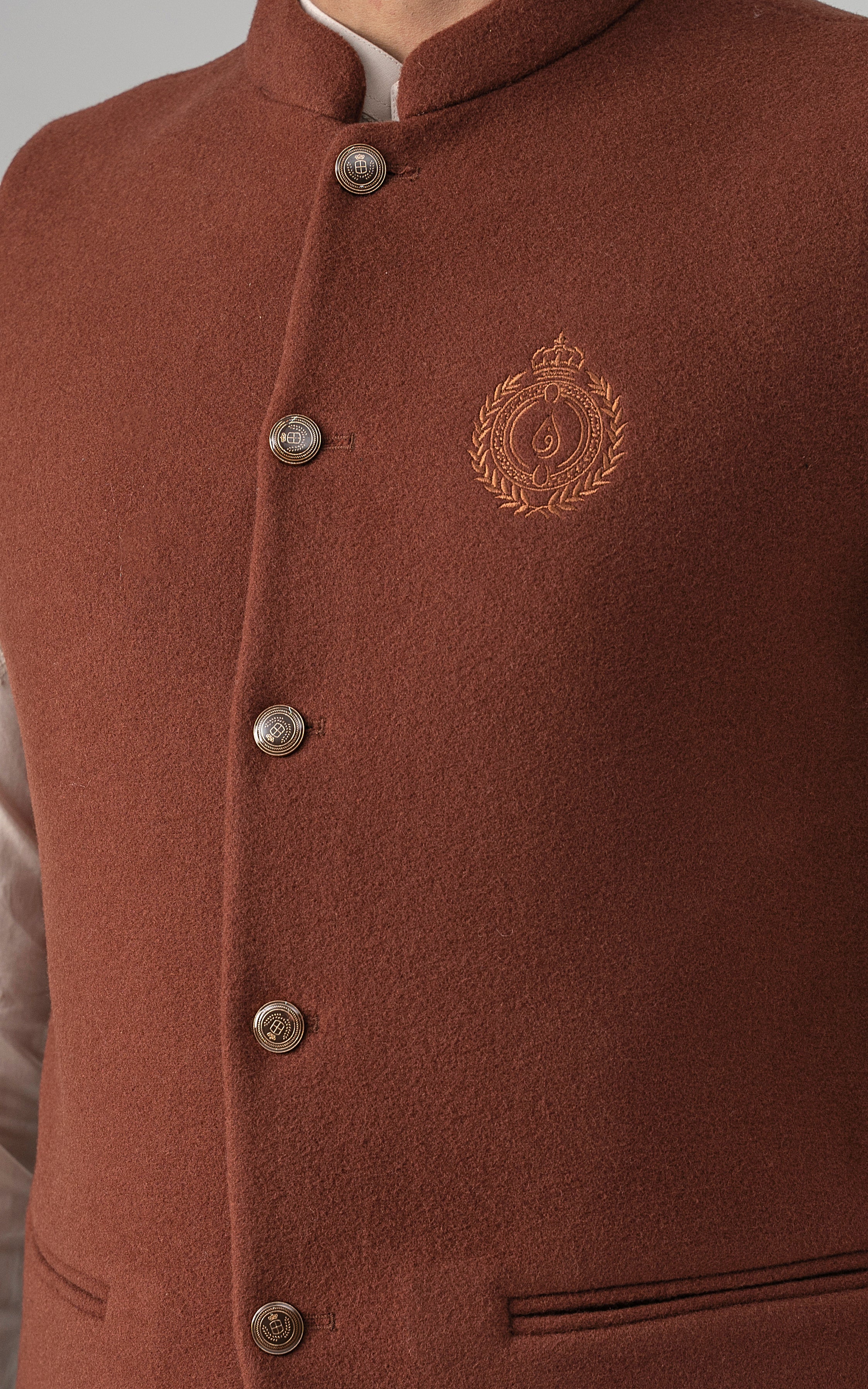 Rust wool-blend waistcoat front close-up with metal buttons and crest badge