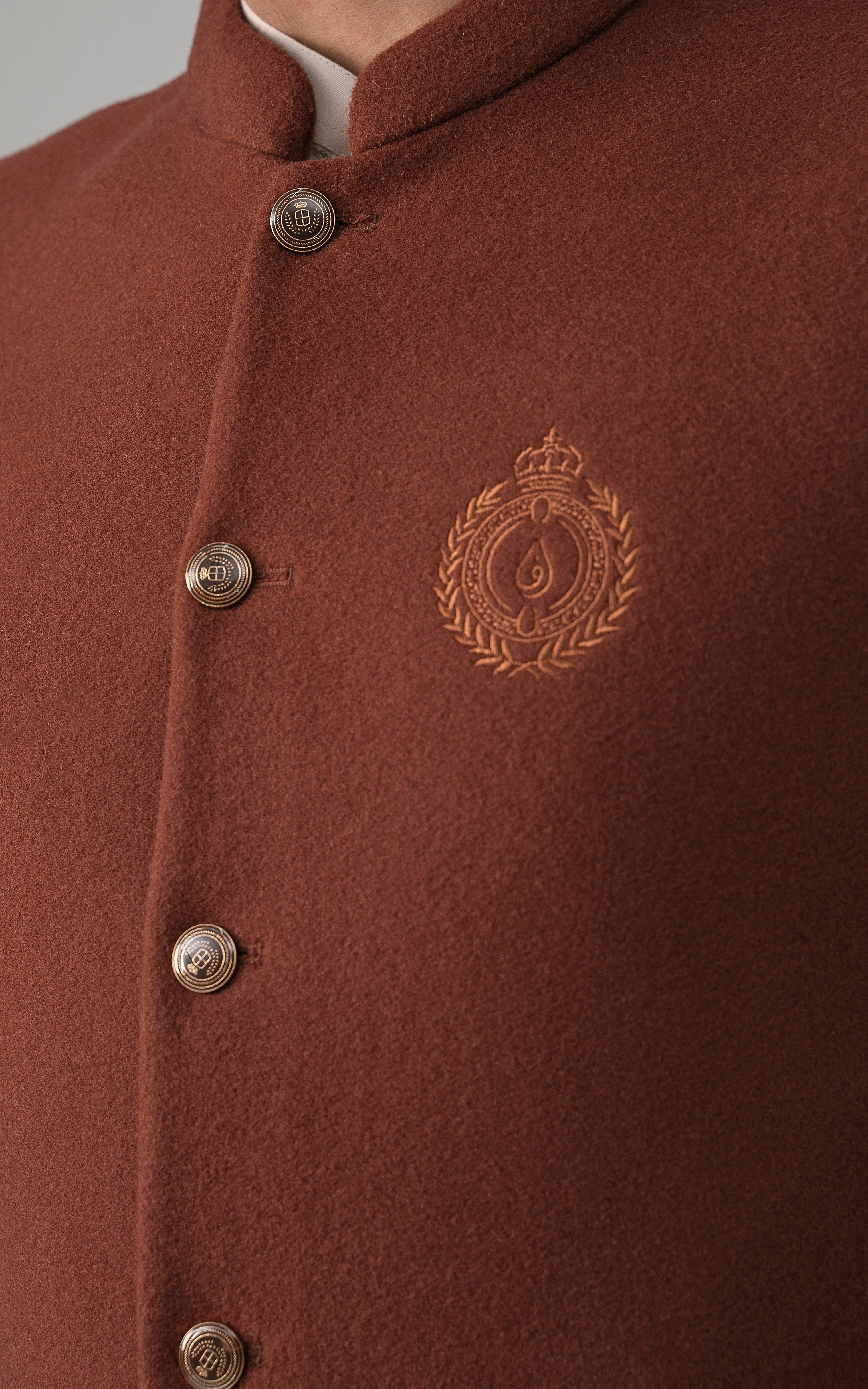 Rust wool-blend waistcoat close-up with stand collar, buttons, and crest emblem