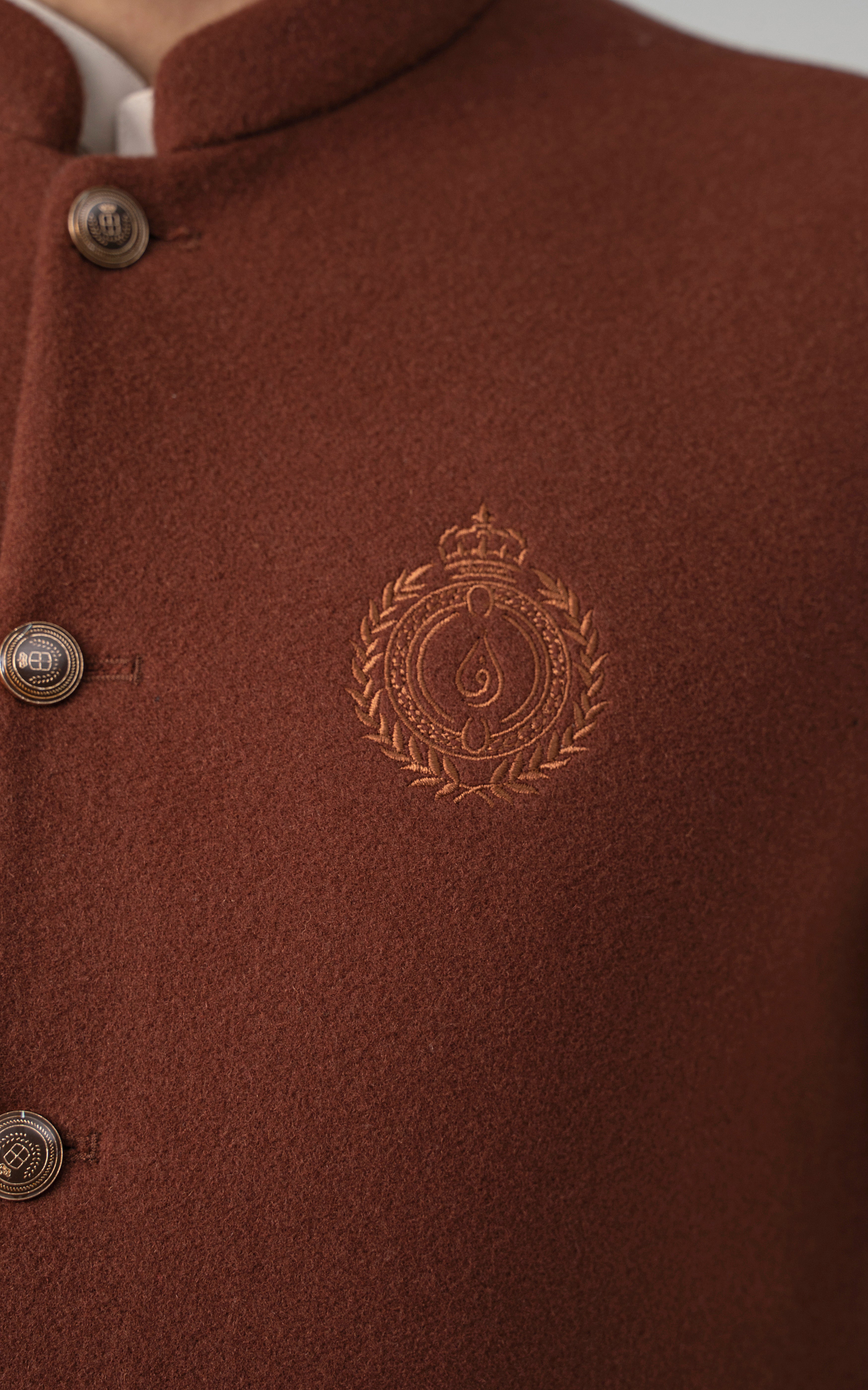 Rust wool-blend waistcoat close-up of crest emblem and textured fabric