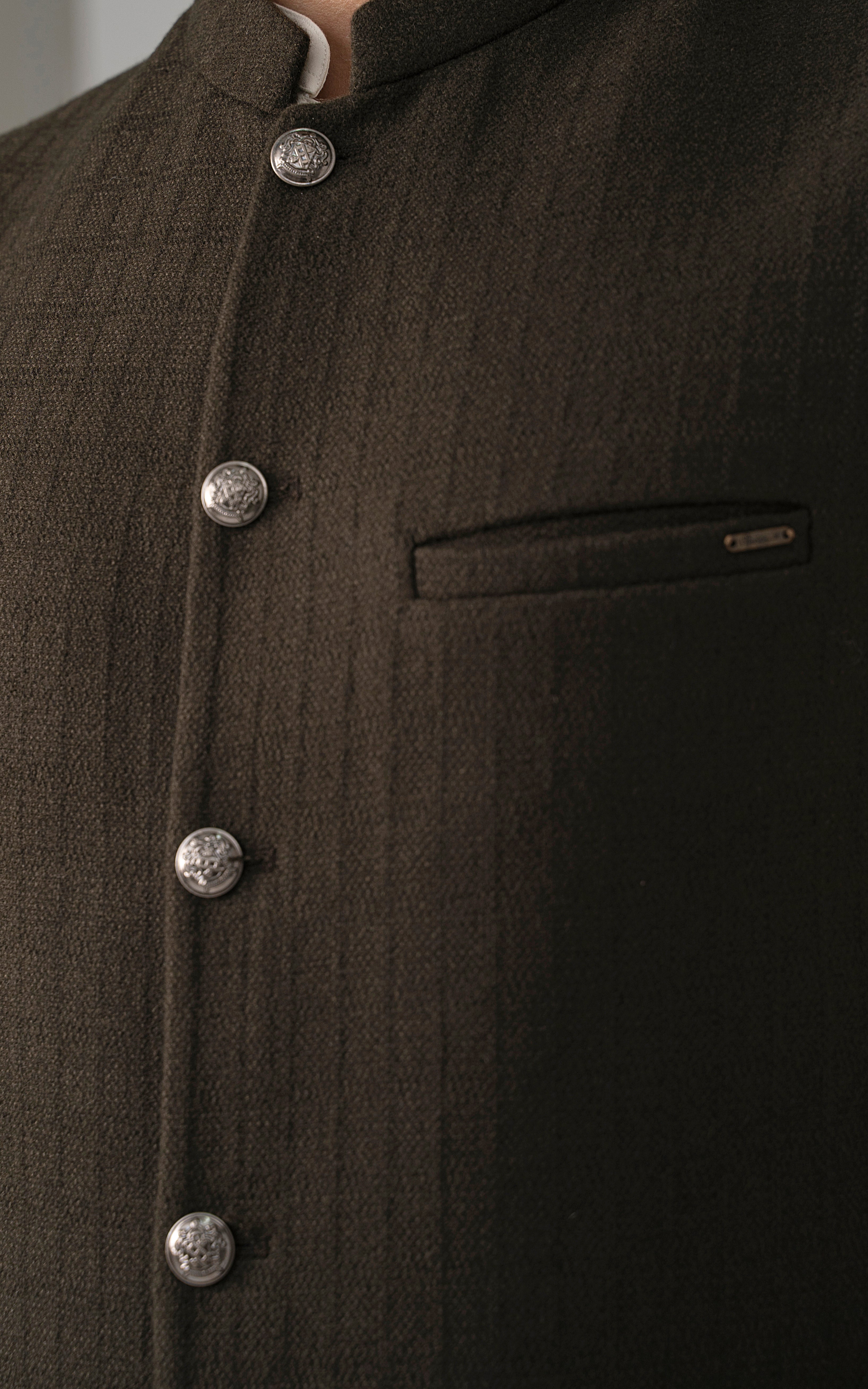 Dark olive textured waistcoat close-up of metal buttons and chest welt pocket