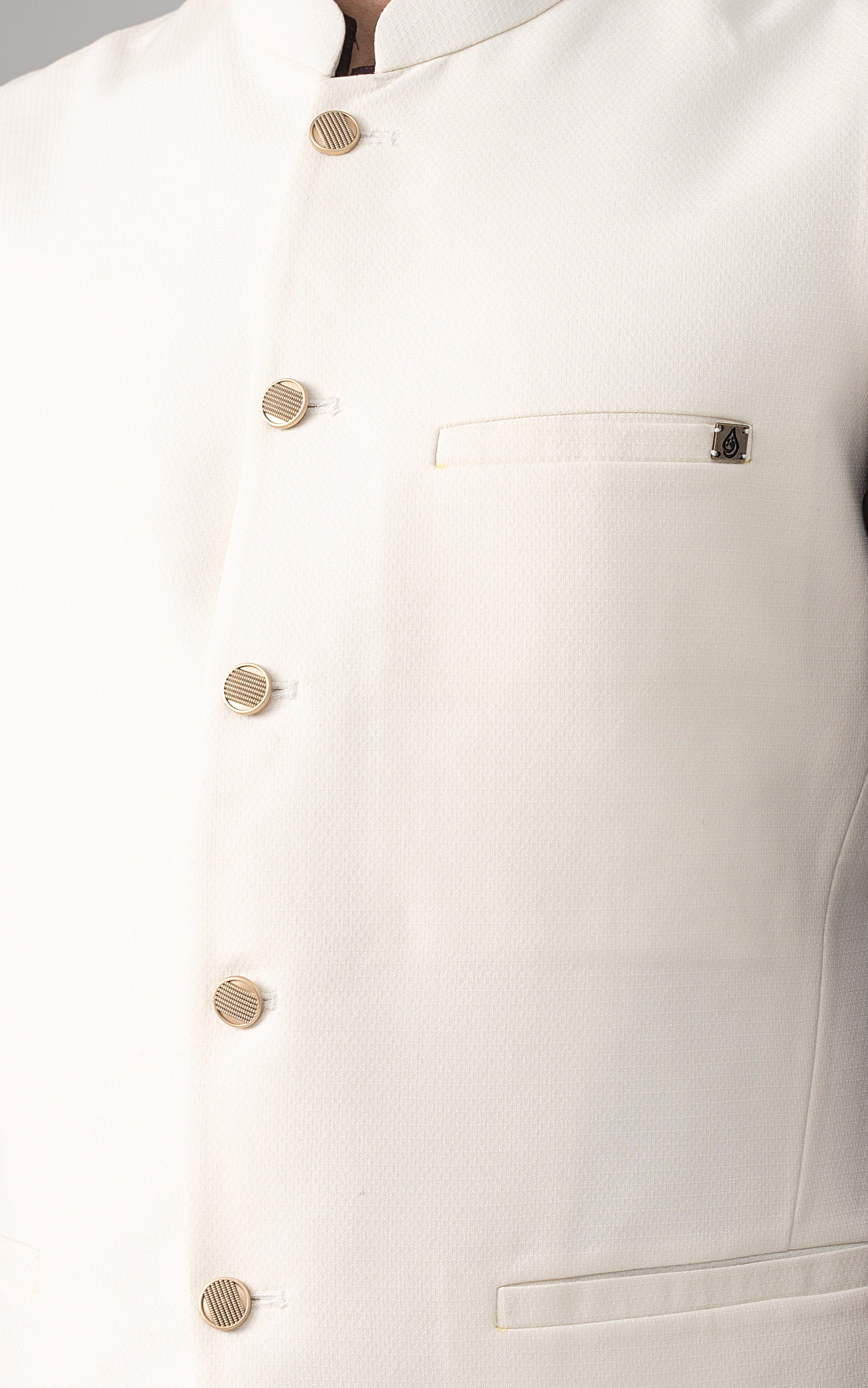 Off-white textured waistcoat close-up: gold buttons and chest welt pocket.