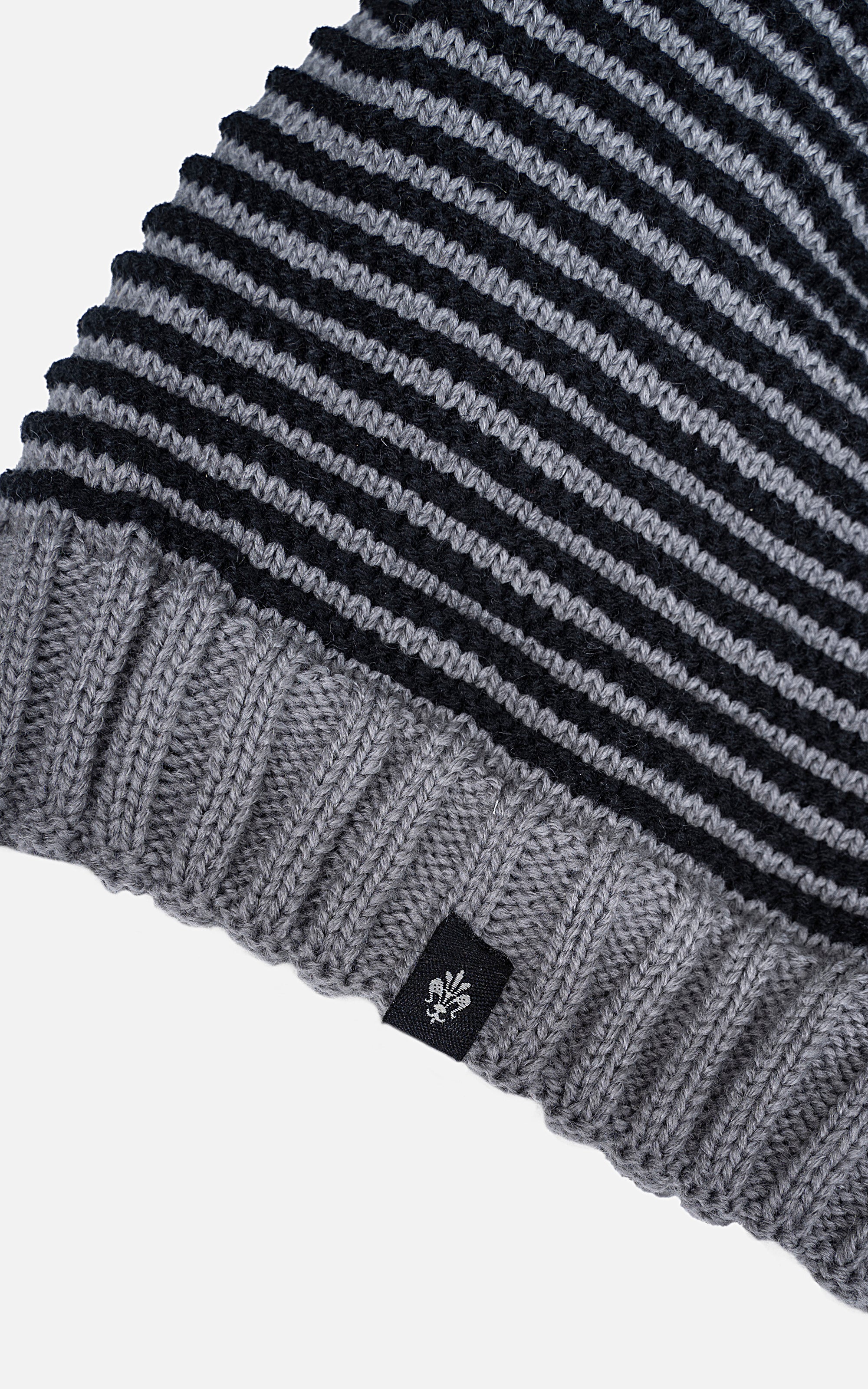 Wool cap cuff detail with gray ribbing and navy-and-white stripe knit, small leaf patch
