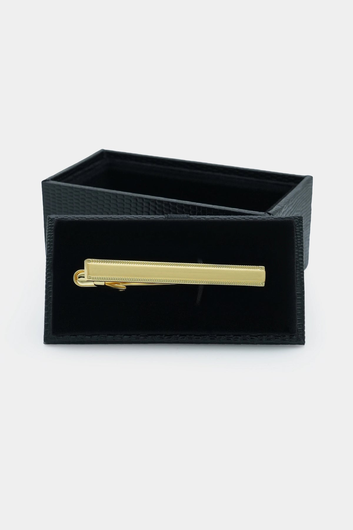 Gold tie pin inside black presentation box, bar with clasp visible.