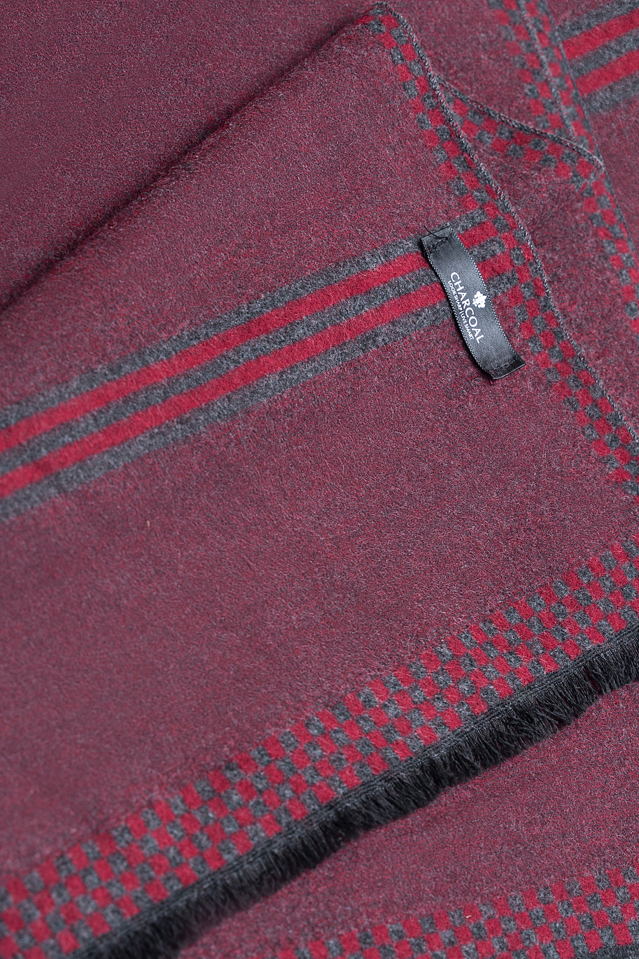 Closeup burgundy scarf corner with red and blue stripe trim and fringed edge