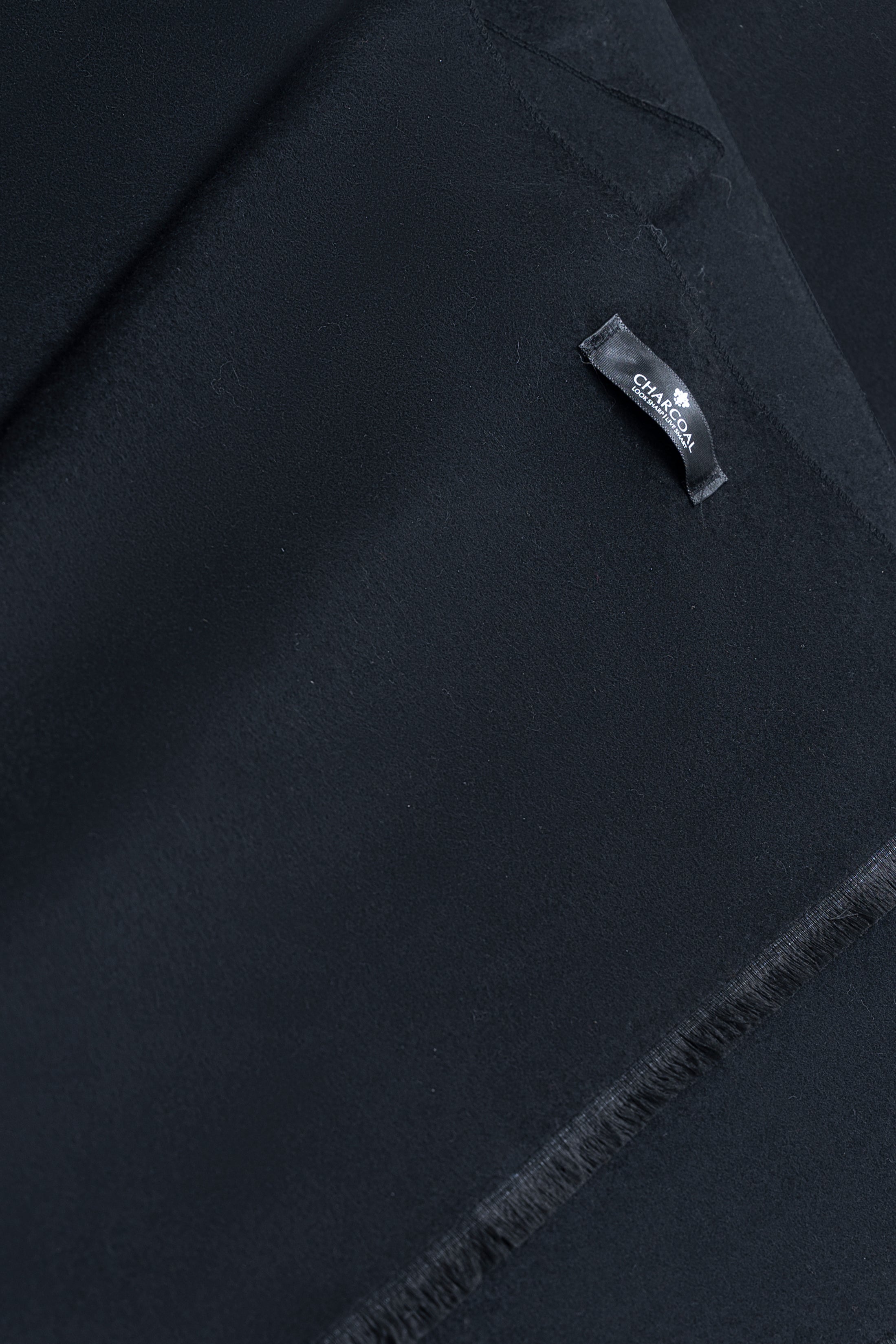 Dark scarf close-up with woven logo label and subtle fabric texture