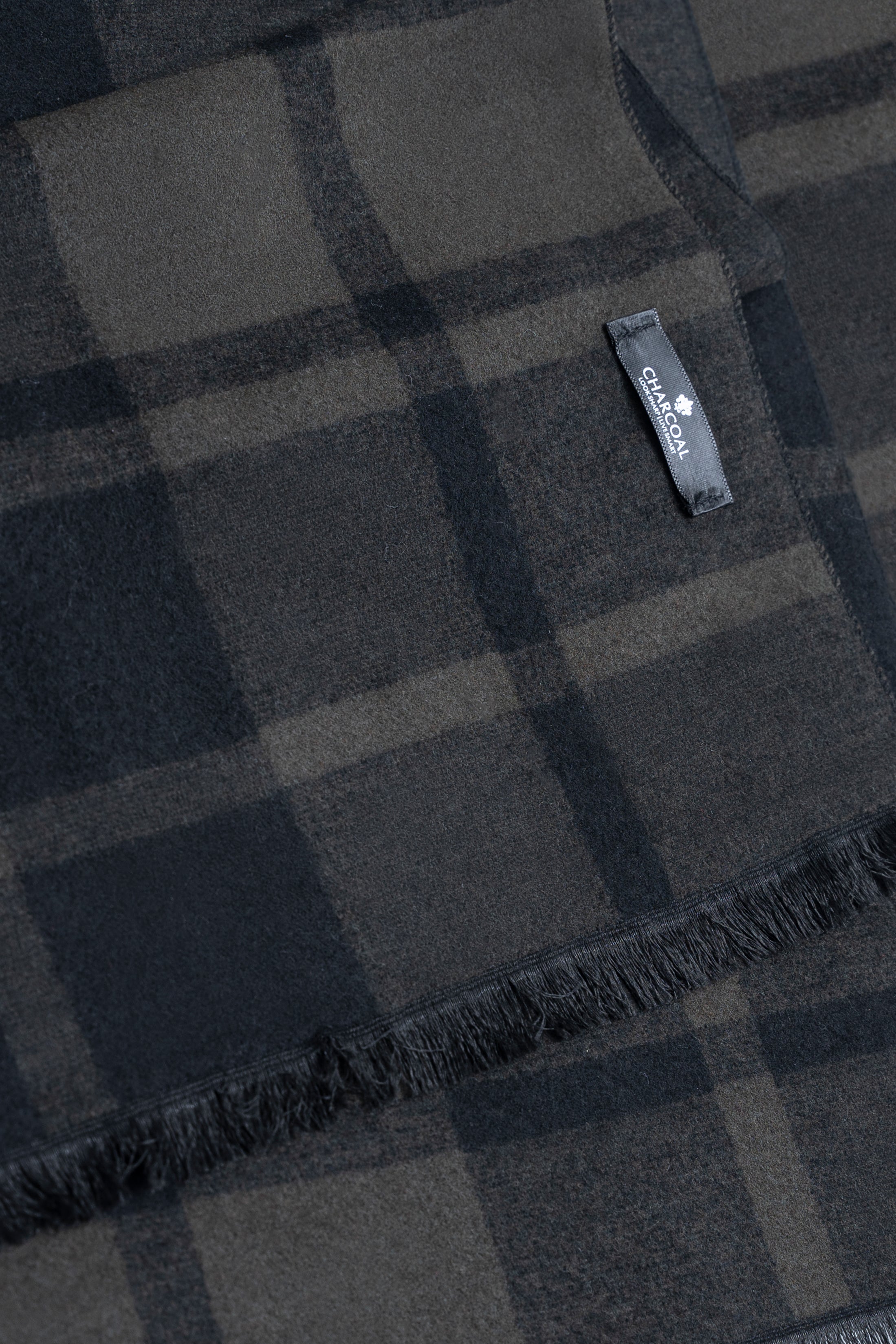 Plaid scarf fabric detail with brand label and fringed edge