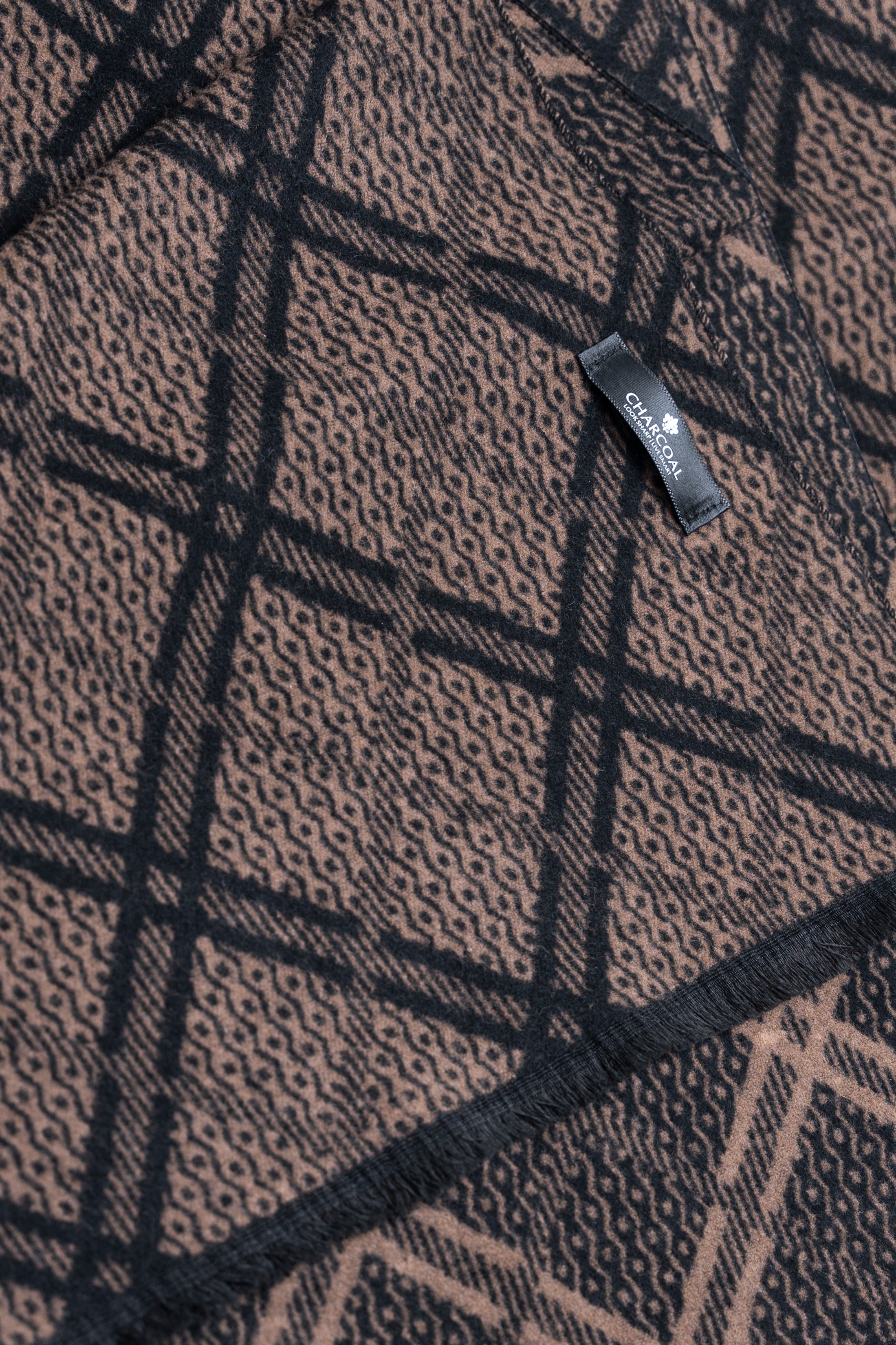 Scarf fabric close-up with textured weave and dark plaid grid, brand tag