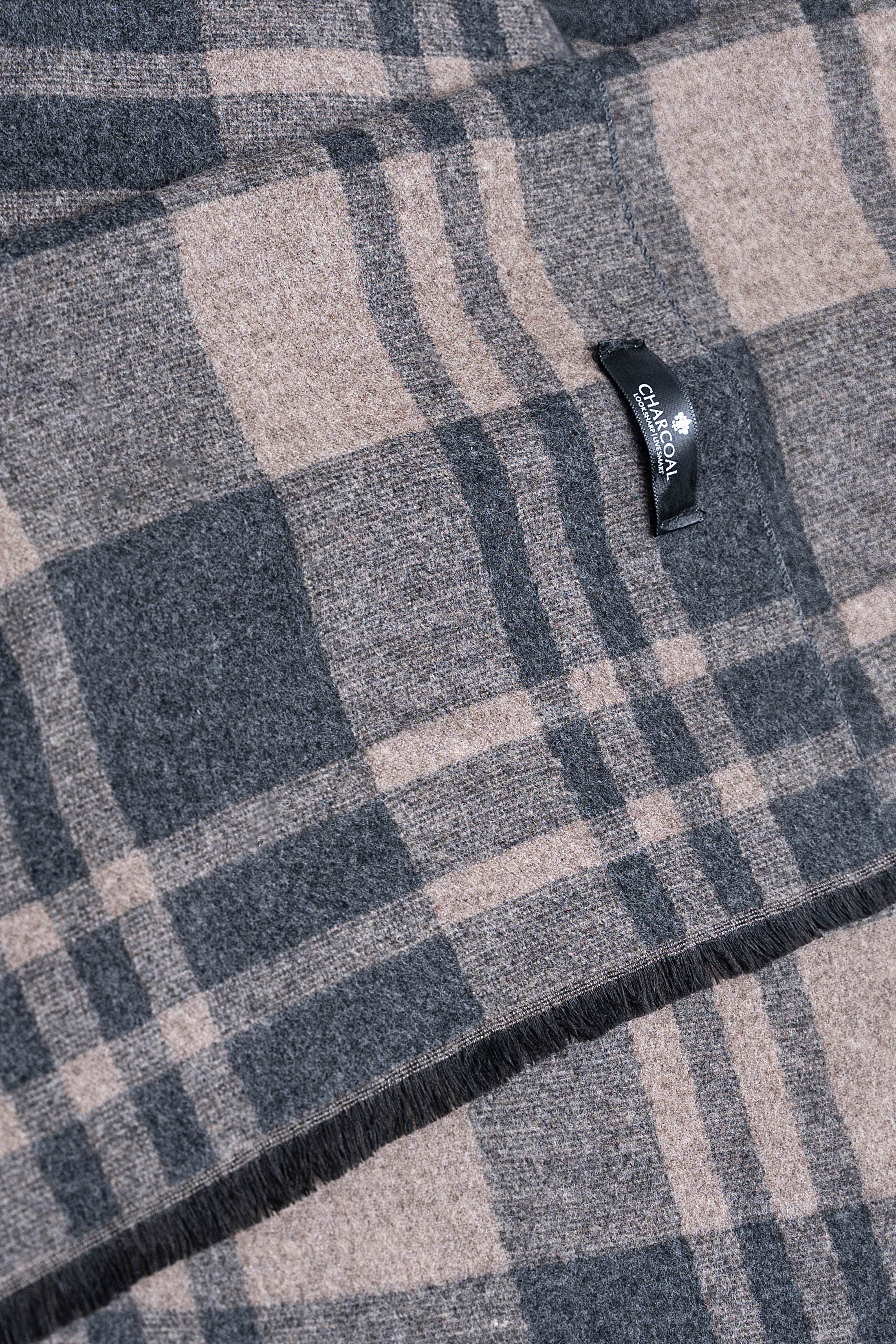 Close-up plaid scarf fabric with dark and beige checks and a small fabric tag