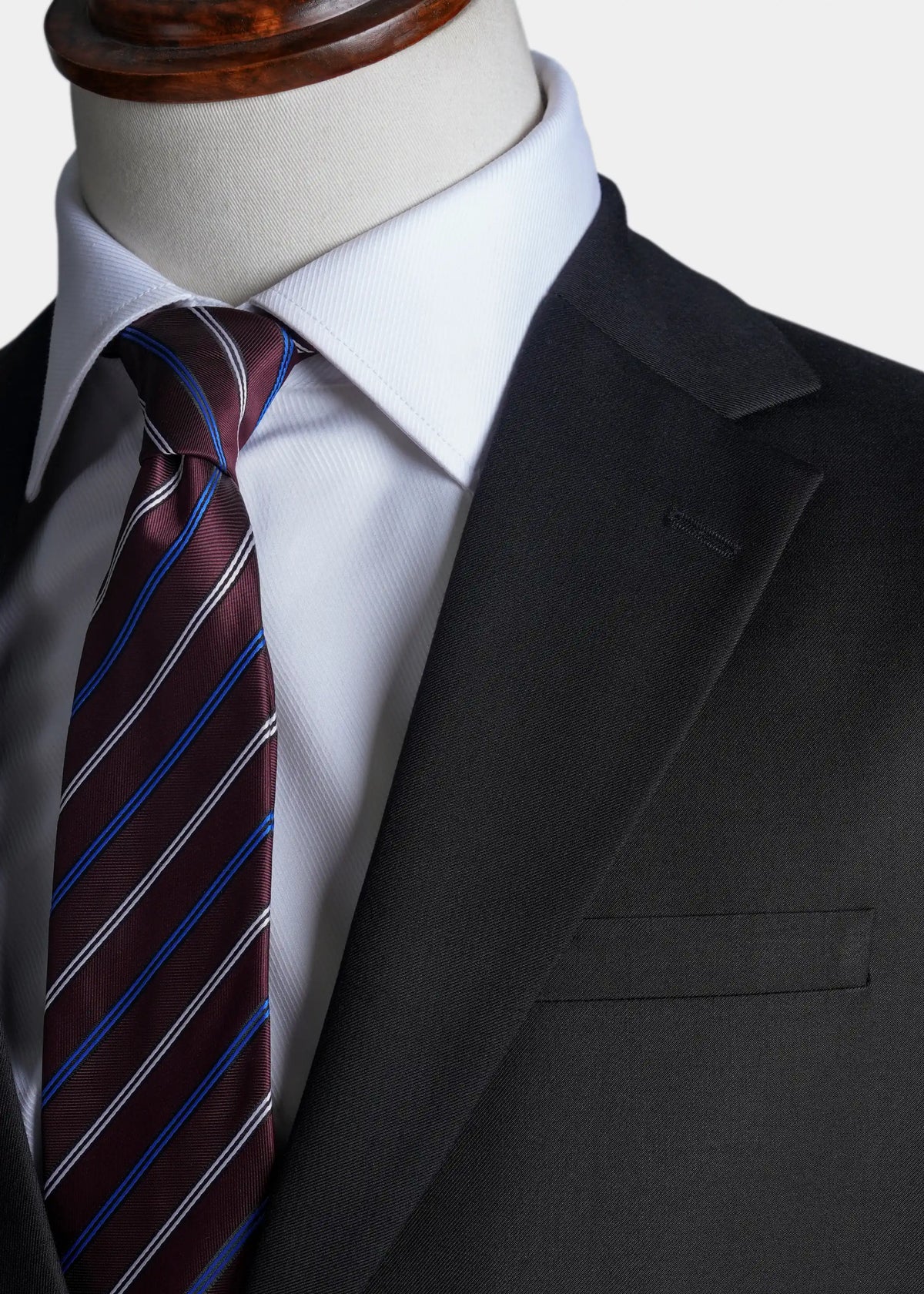 Black suit jacket lapel and breast pocket with striped tie and white dress shirt