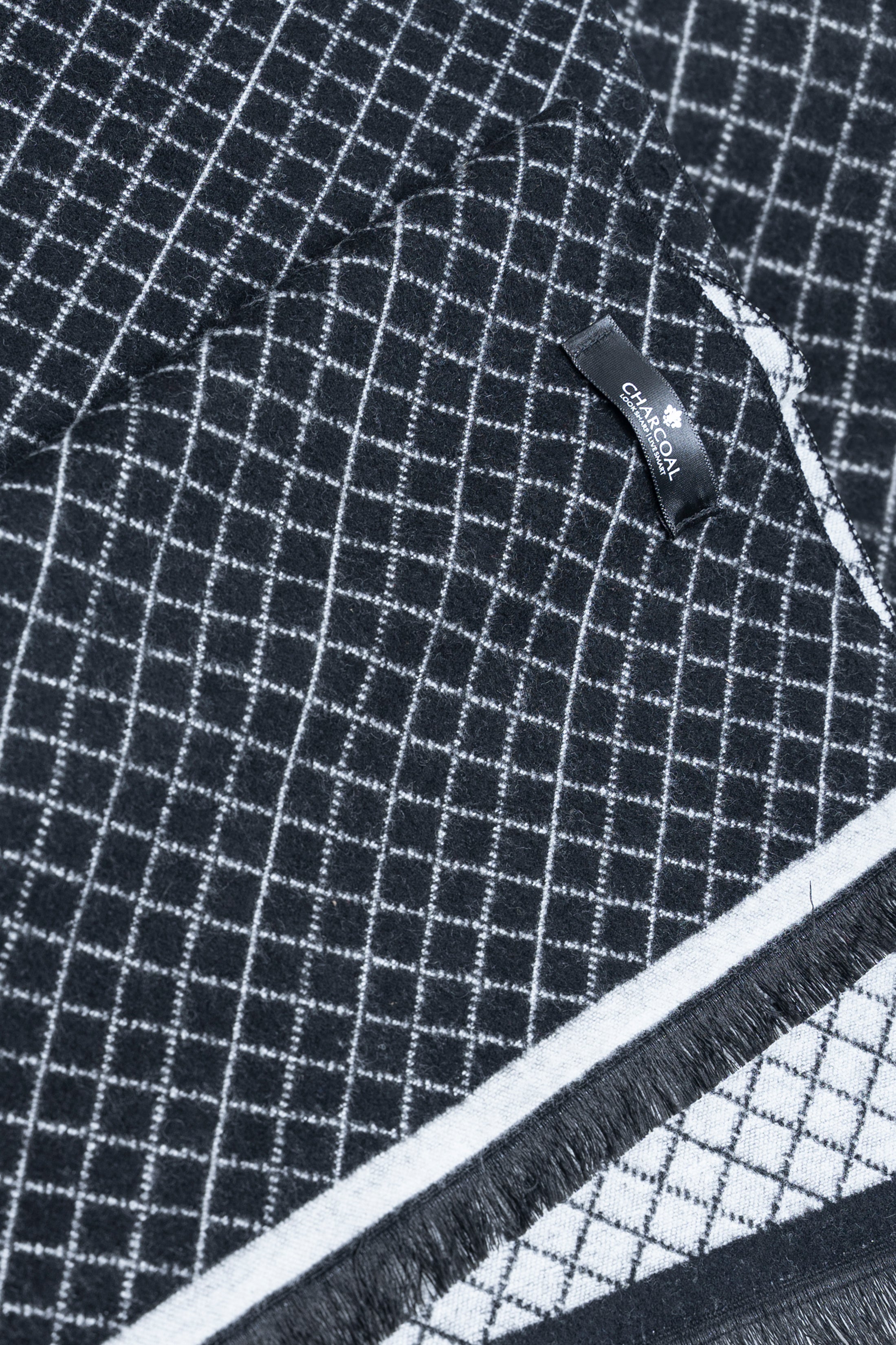 Navy grid scarf close-up with white check lines, brand tag, and fringed edge