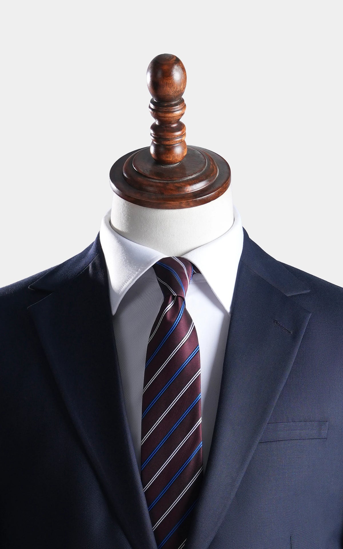 Navy notch-lapel blazer with striped necktie and white dress shirt on mannequin