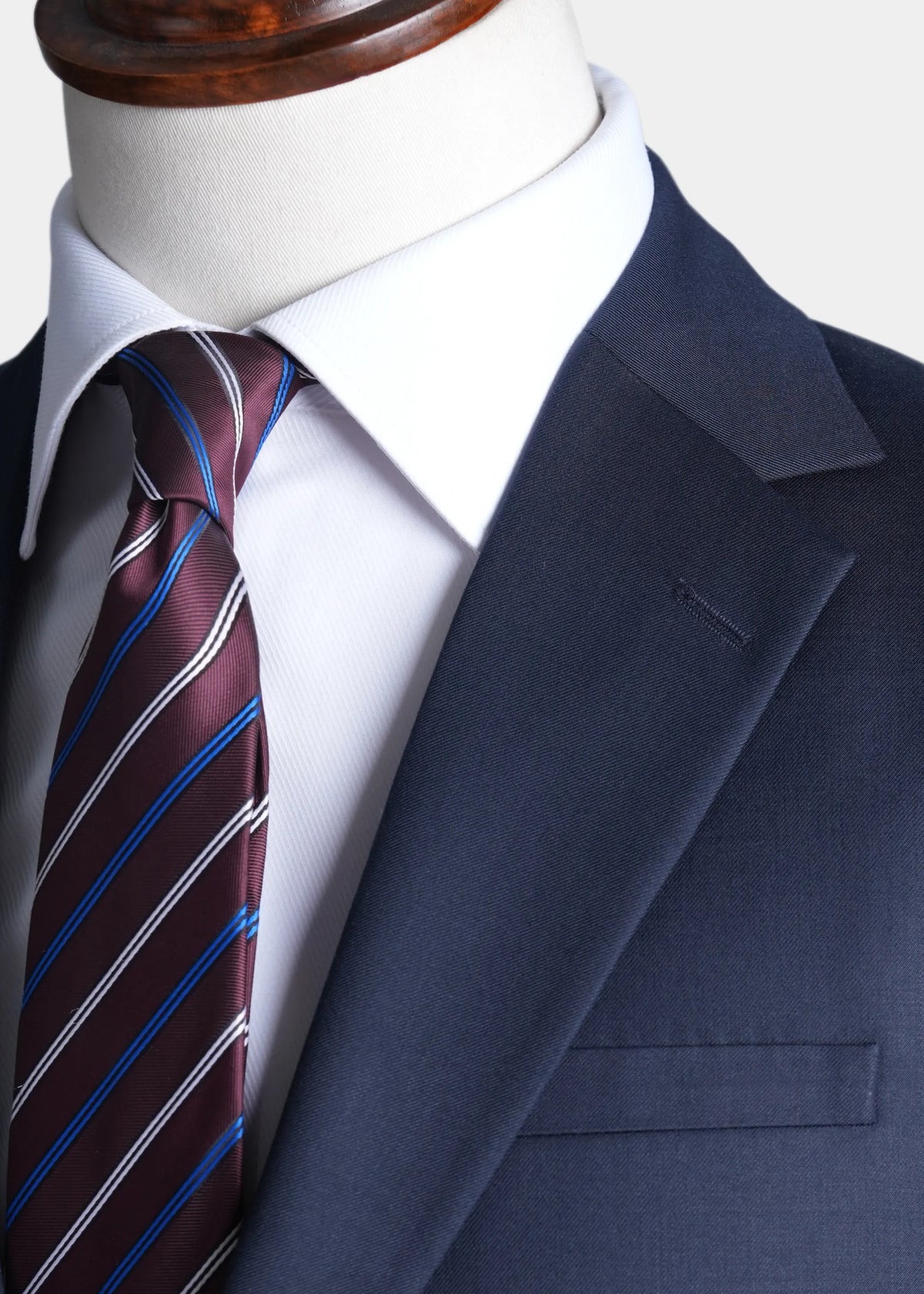 Navy notch-lapel dress jacket with striped tie and white dress shirt collar