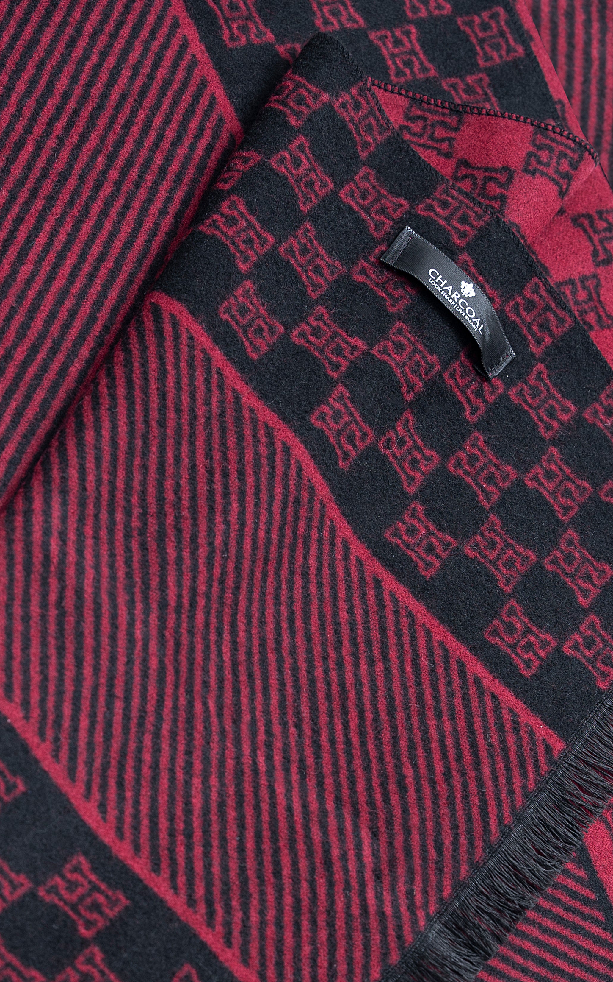 Close-up scarf fabric with burgundy woven motif pattern, edge stitching, and tag