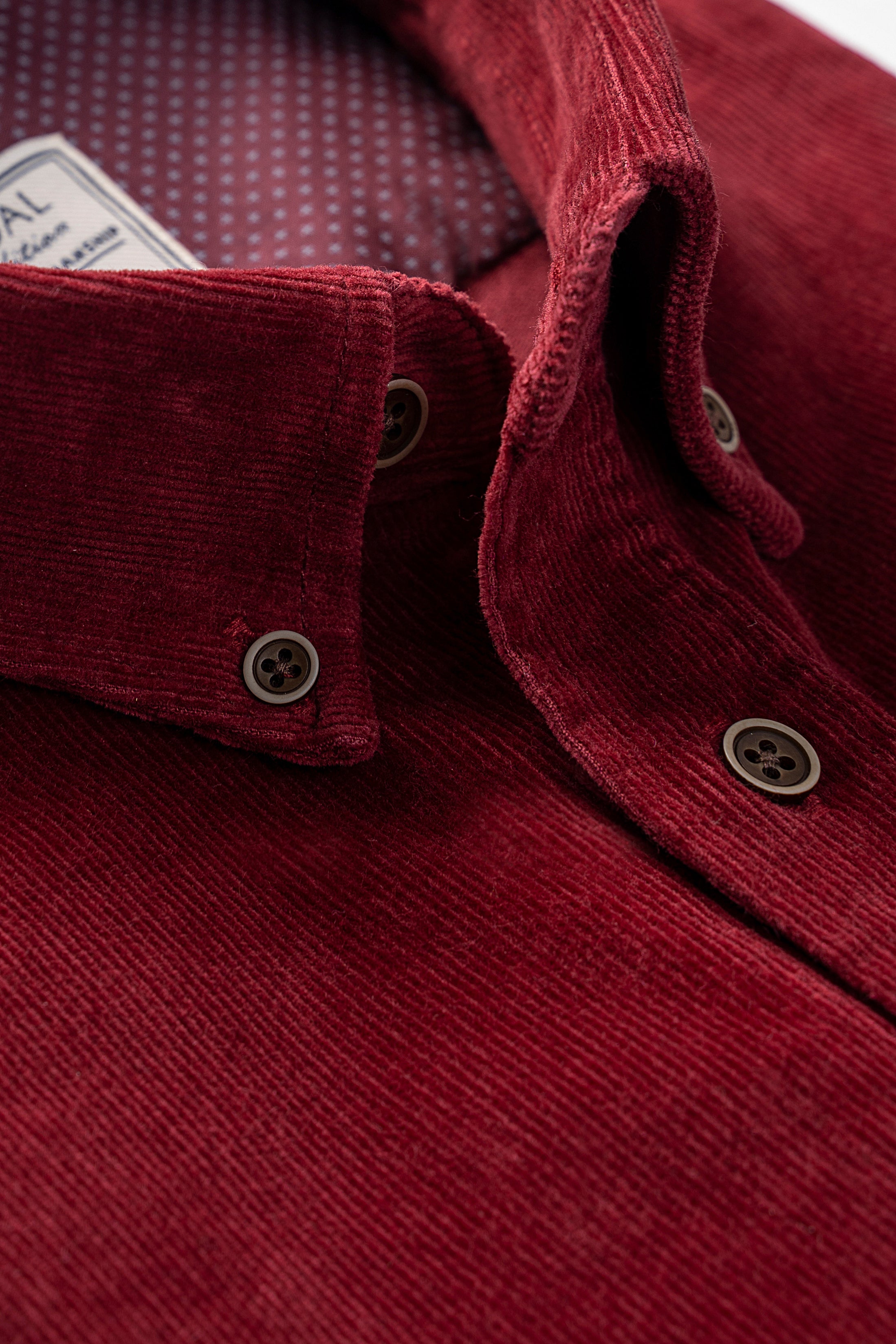 Maroon corduroy shirt collar with dark button details and buttoned cuffs