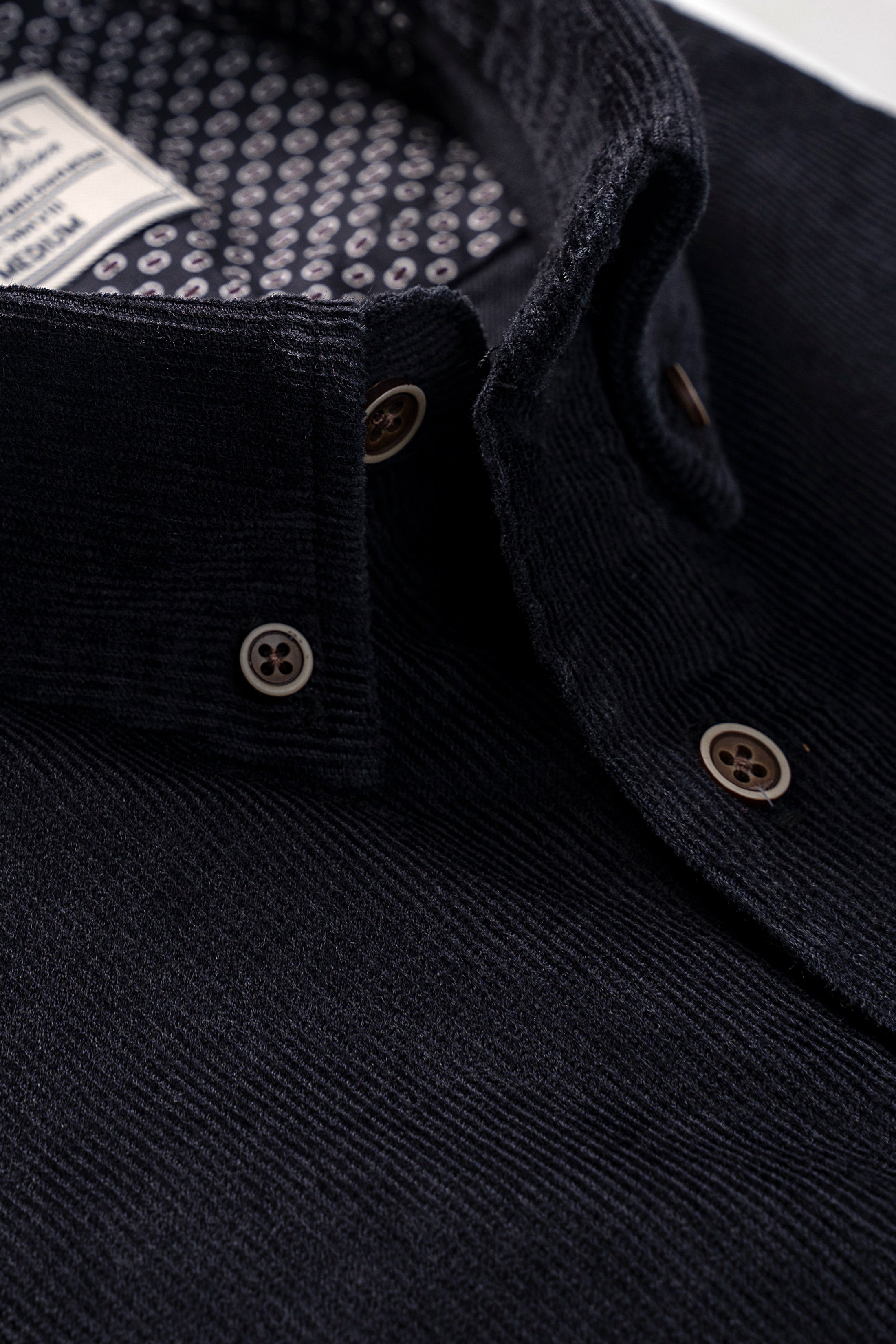 Black corduroy shirt close-up of buttons and buttoned cuff on placket
