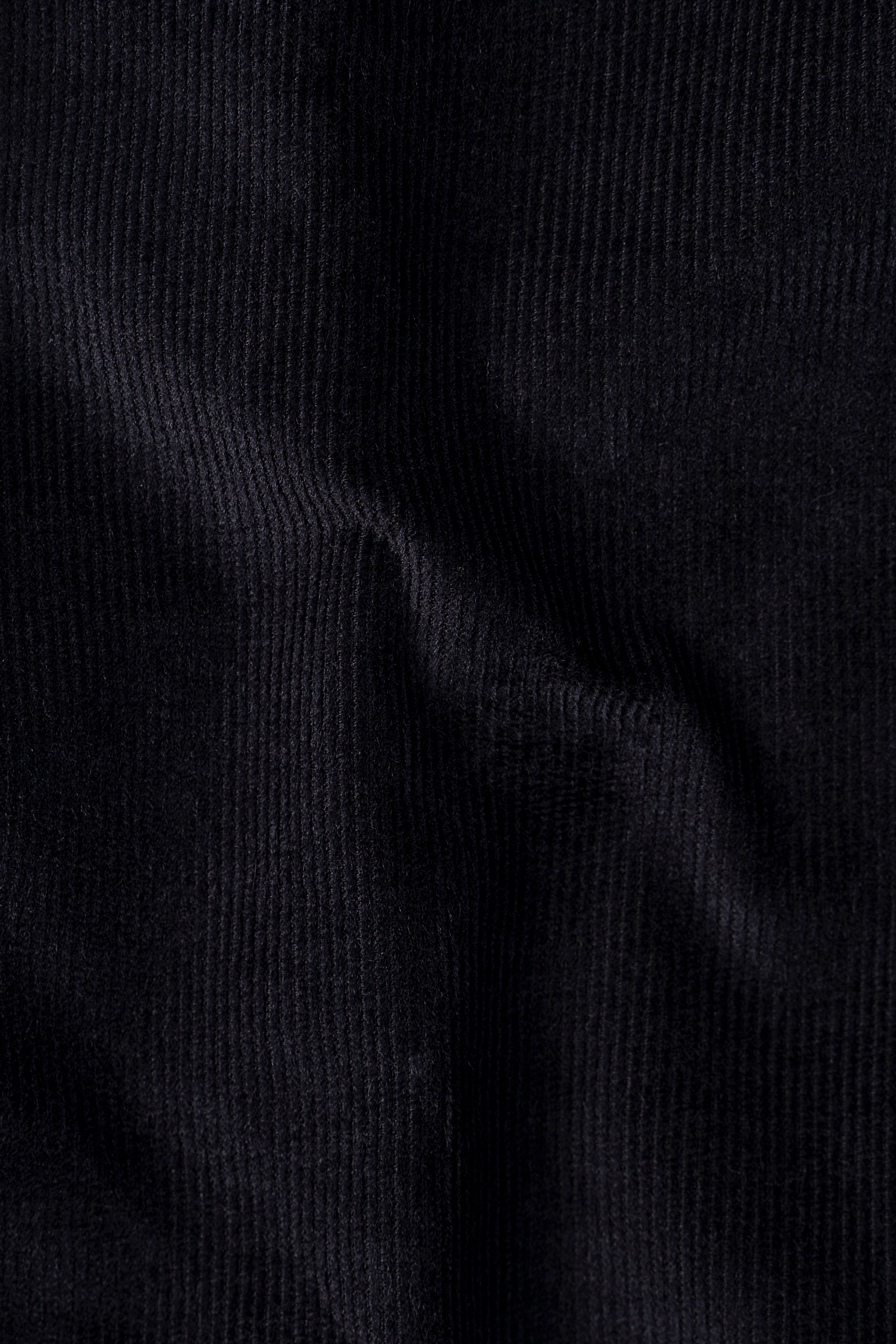 Black corduroy shirt fabric close-up showing ribbed texture