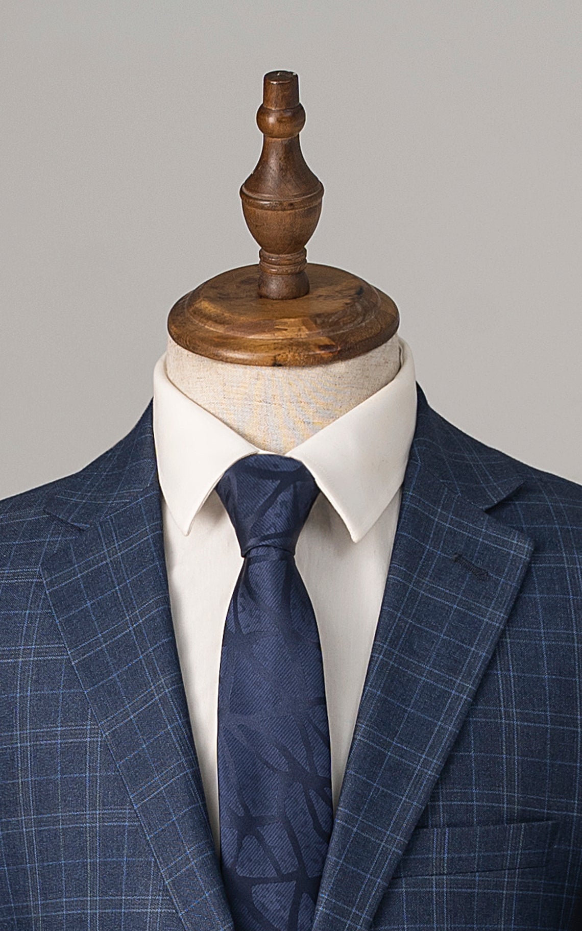 Navy blue suit blazer with blue tie and checked lapels over white shirt