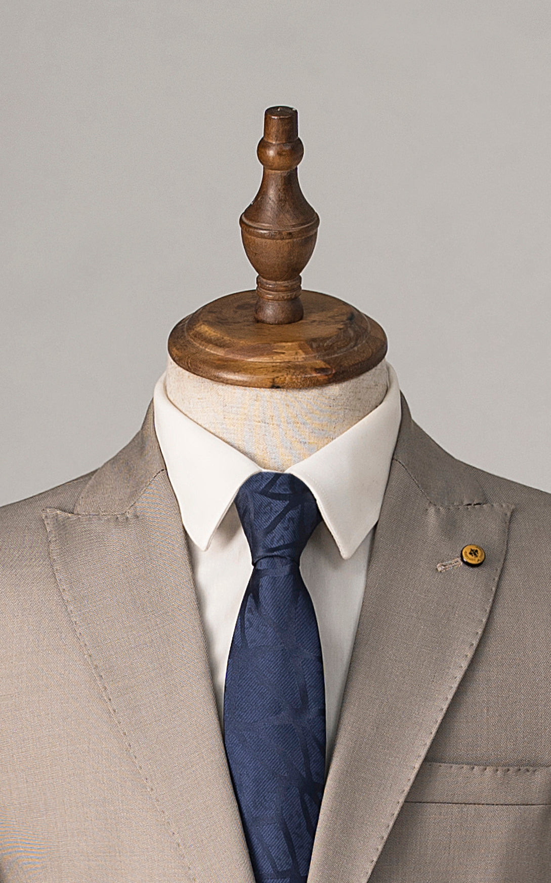 Beige suit jacket with blue tie on a mannequin and white dress shirt collar