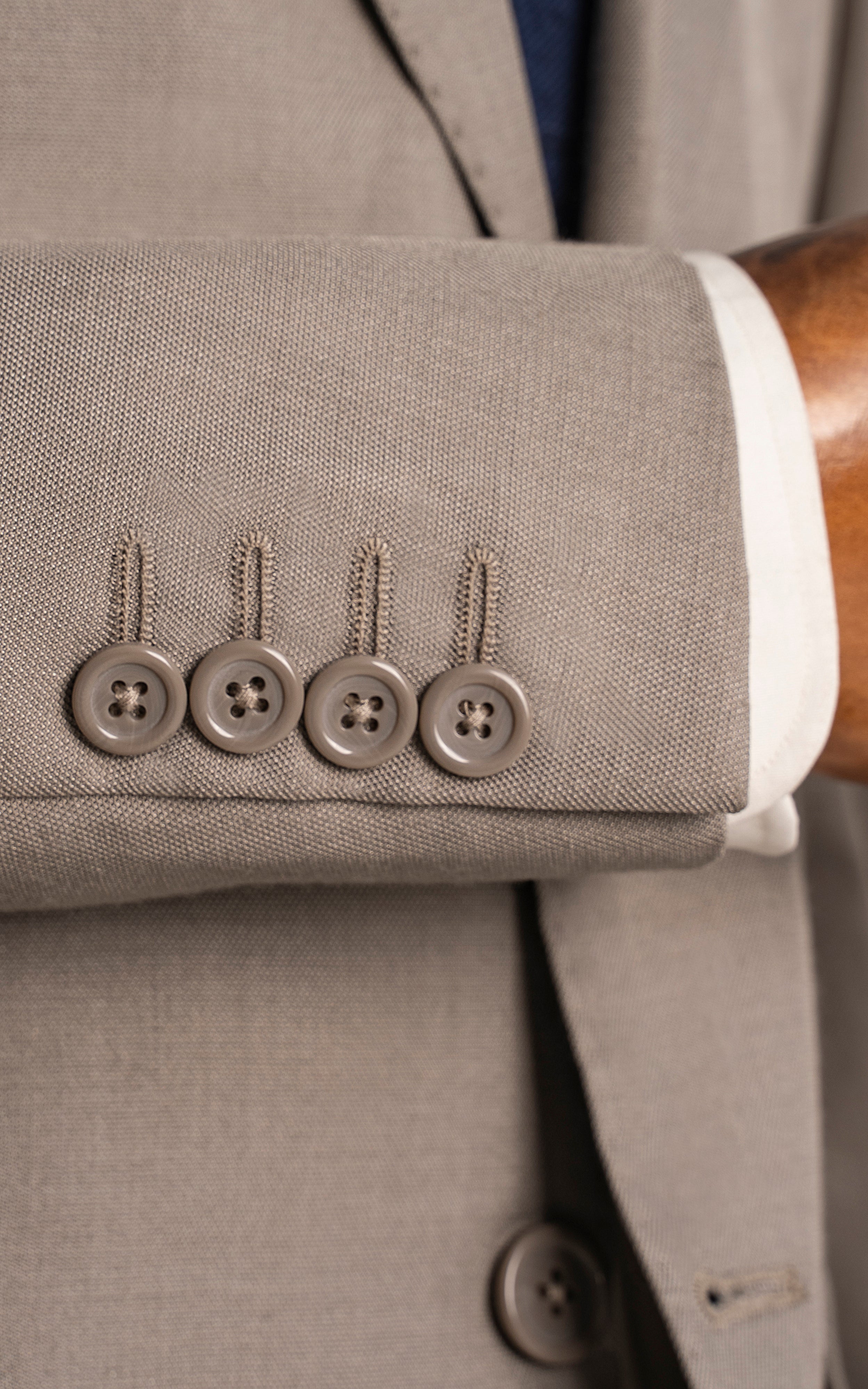 Beige suit sleeve cuff detail with four buttons and white dress shirt cuff