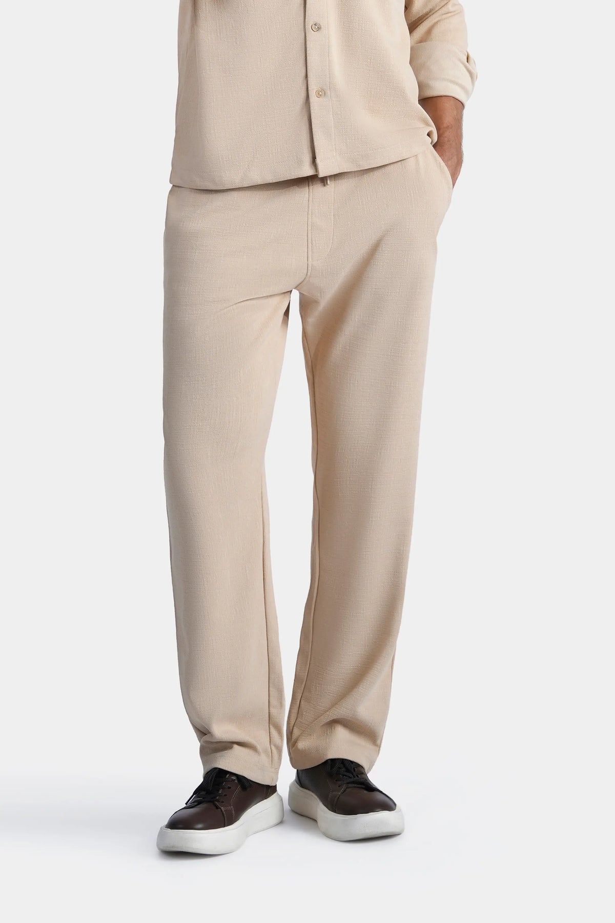 Beige loose-fit trousers with front crease, buttoned fly, and open hem